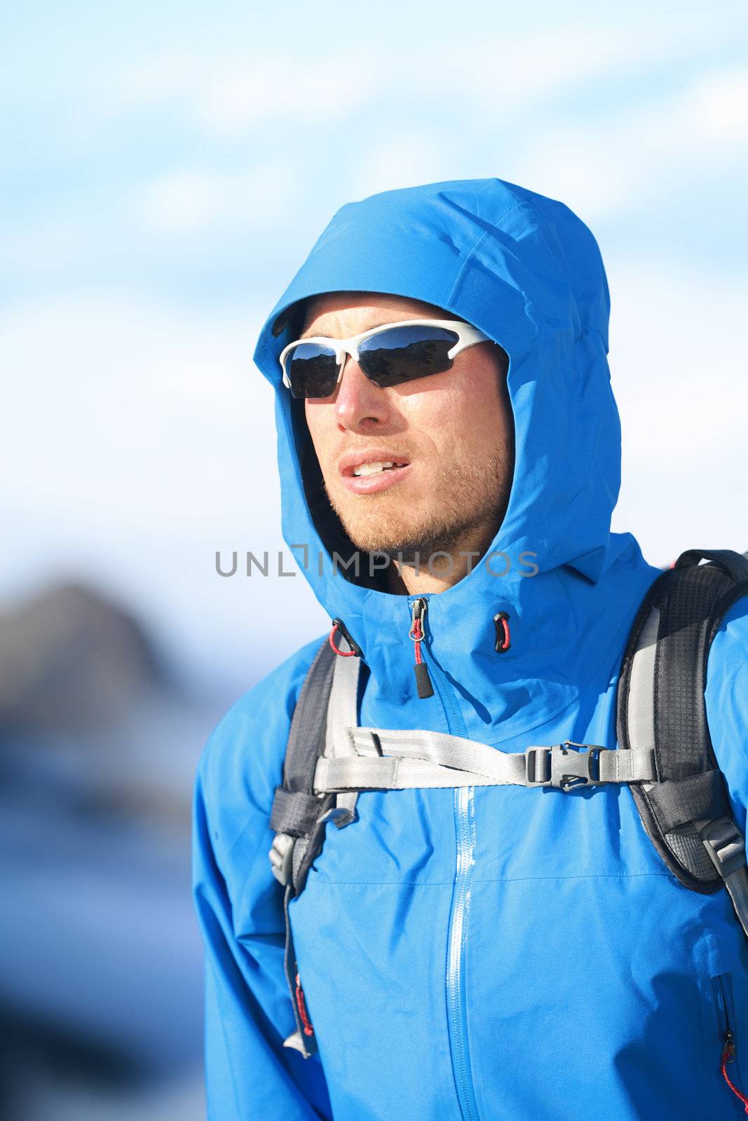 Hiking man - hiker portrait of young male hiker and climber in alpine wear hard shell jacket in high altitude mountain above the clouds.