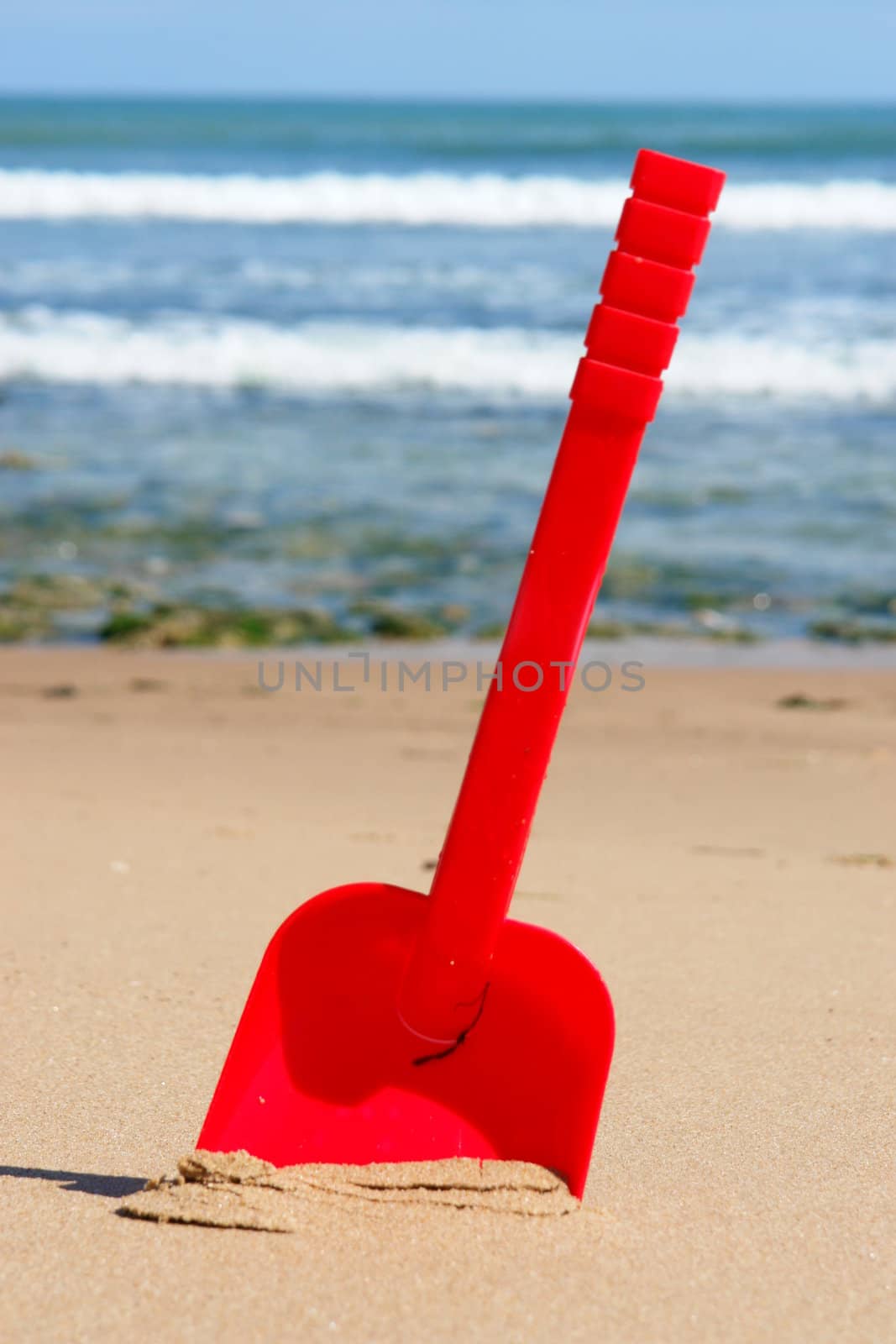 a red shovel at the beach on a sunny day