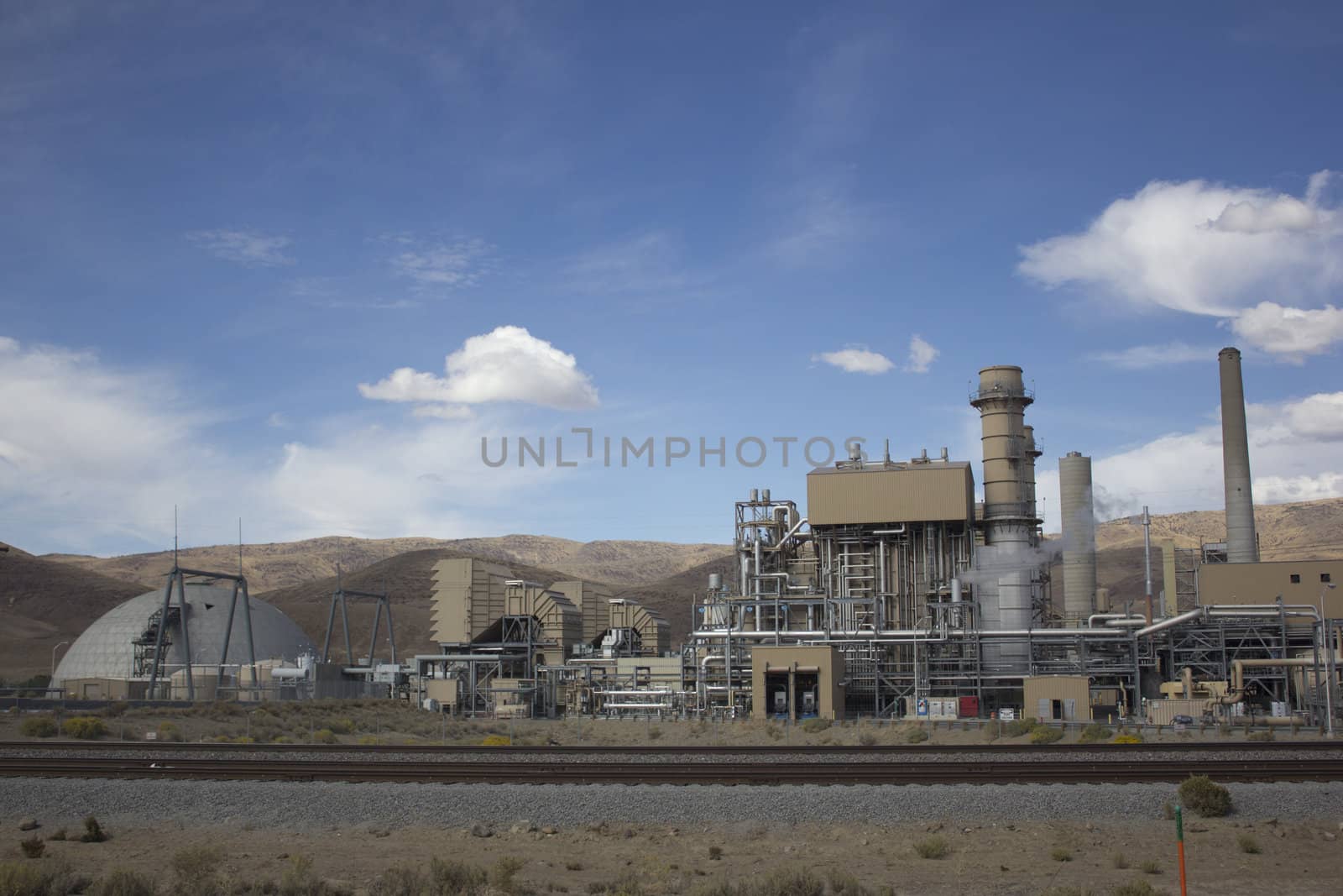 Power plant factory next to train track in the desert by jeremywhat