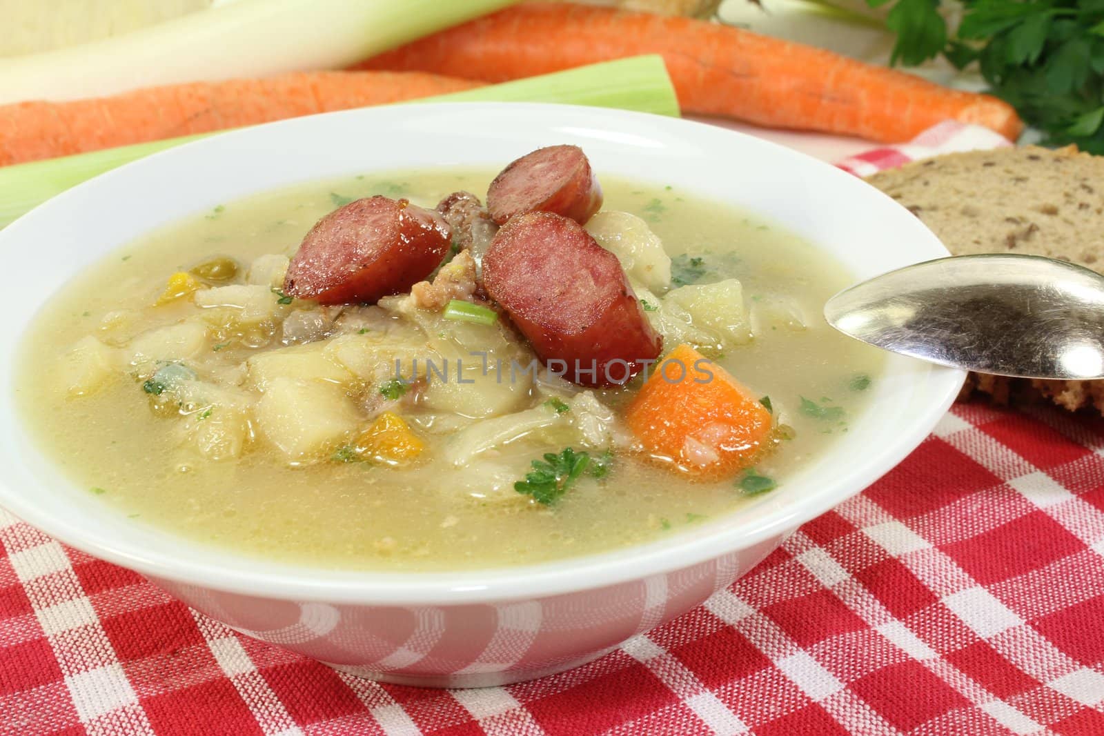 white cabbage soup with vegetables and fried sausage