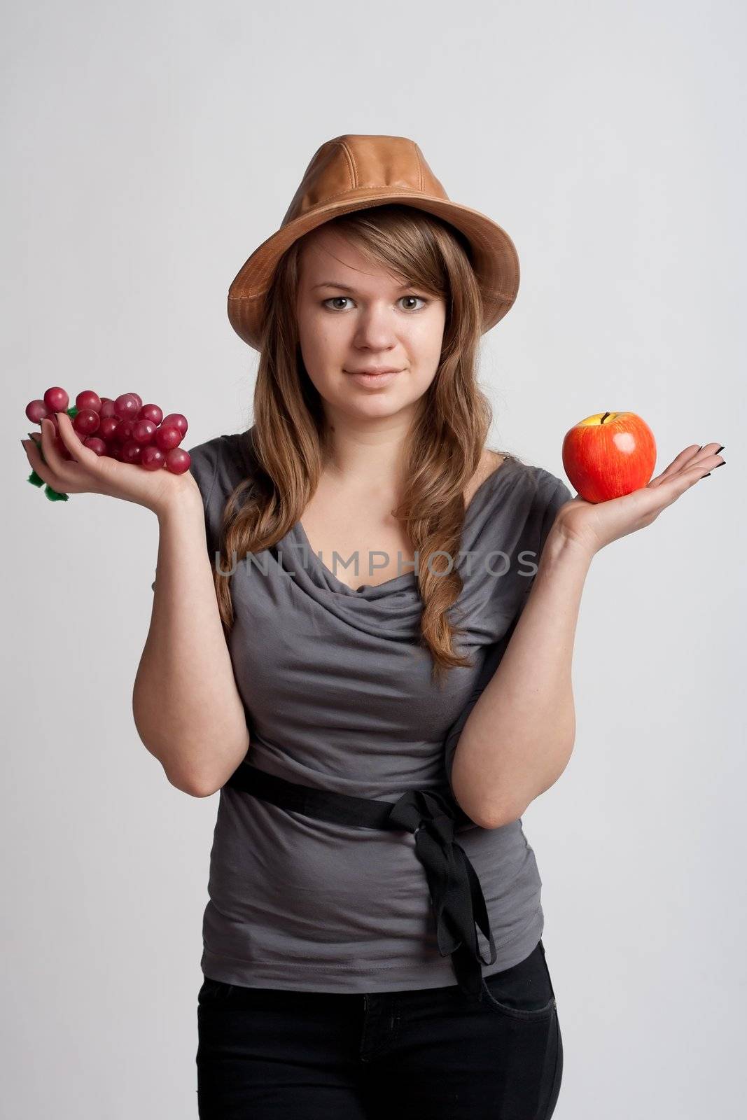 girl on a white background with grapes and apples in the hands of