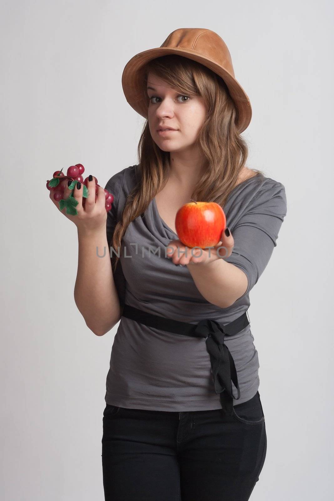 girl on a white background with grapes and apples in the hands of