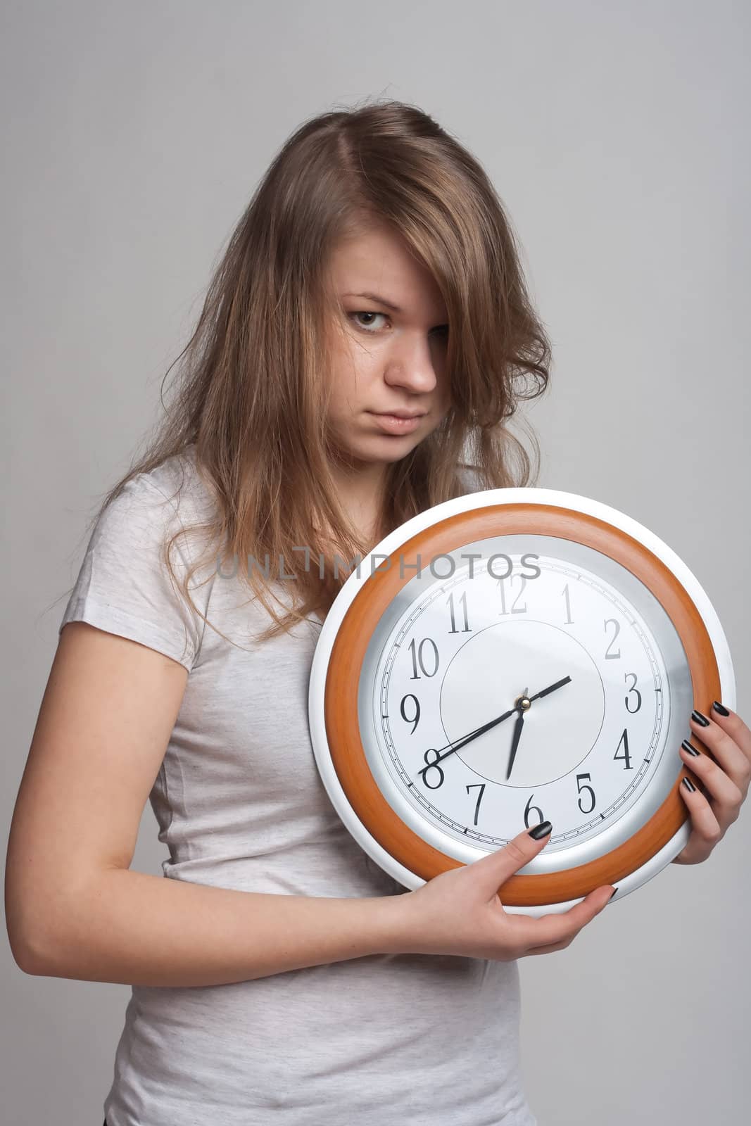 sleeping girl on a white background with a big clock in the hands of which 6.40 am