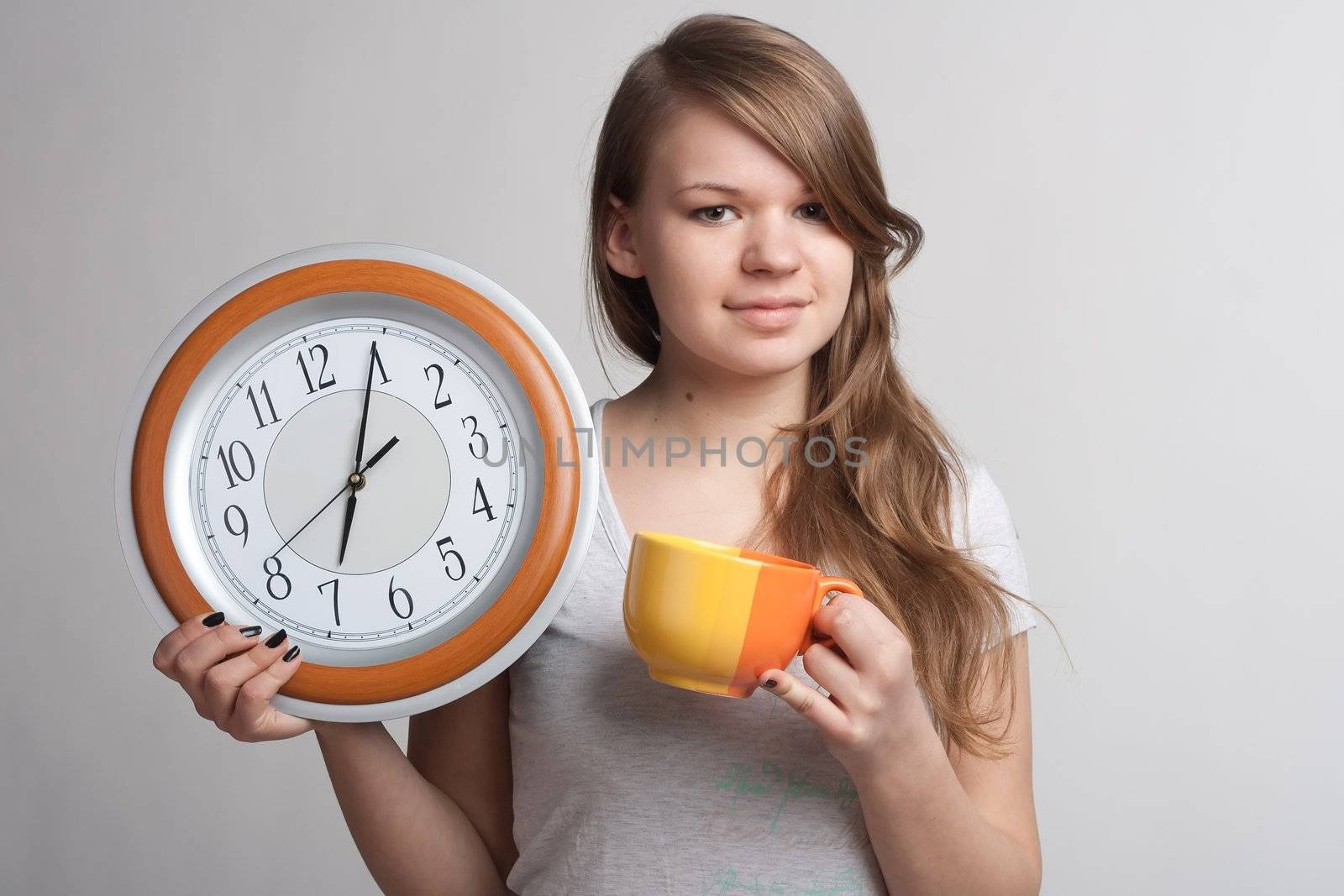 Smiling girl holding in one hand and watch while the other cup