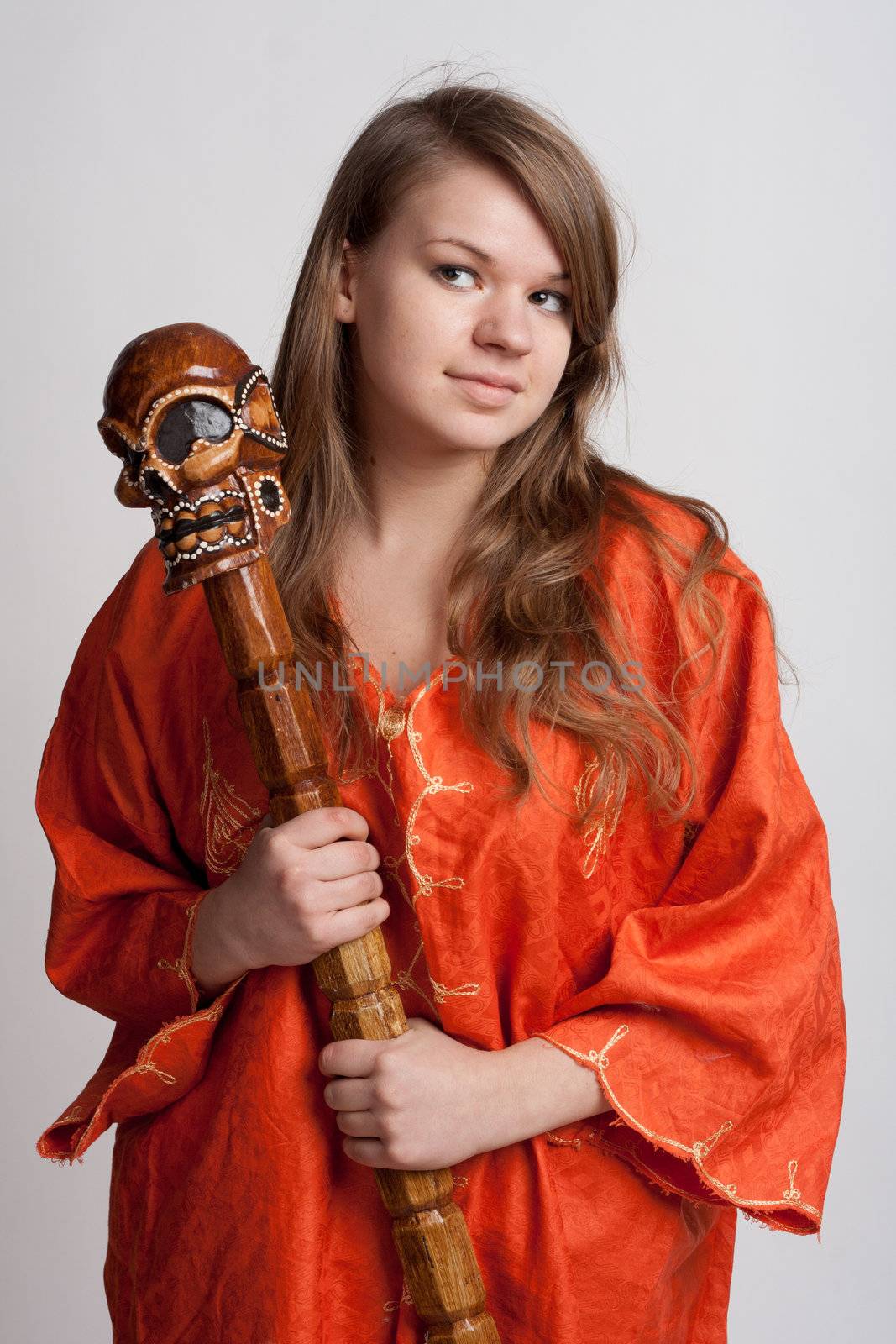 Girl in orange dress on a light background with a staff