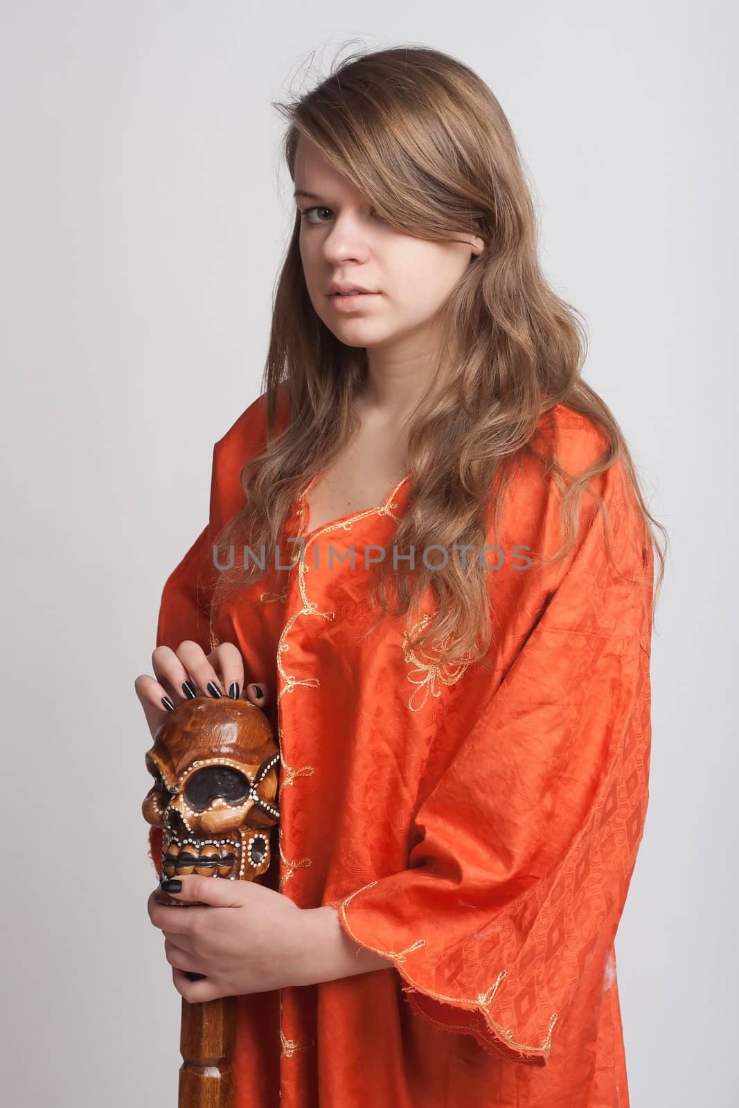 Girl in orange dress on a light background with a staff