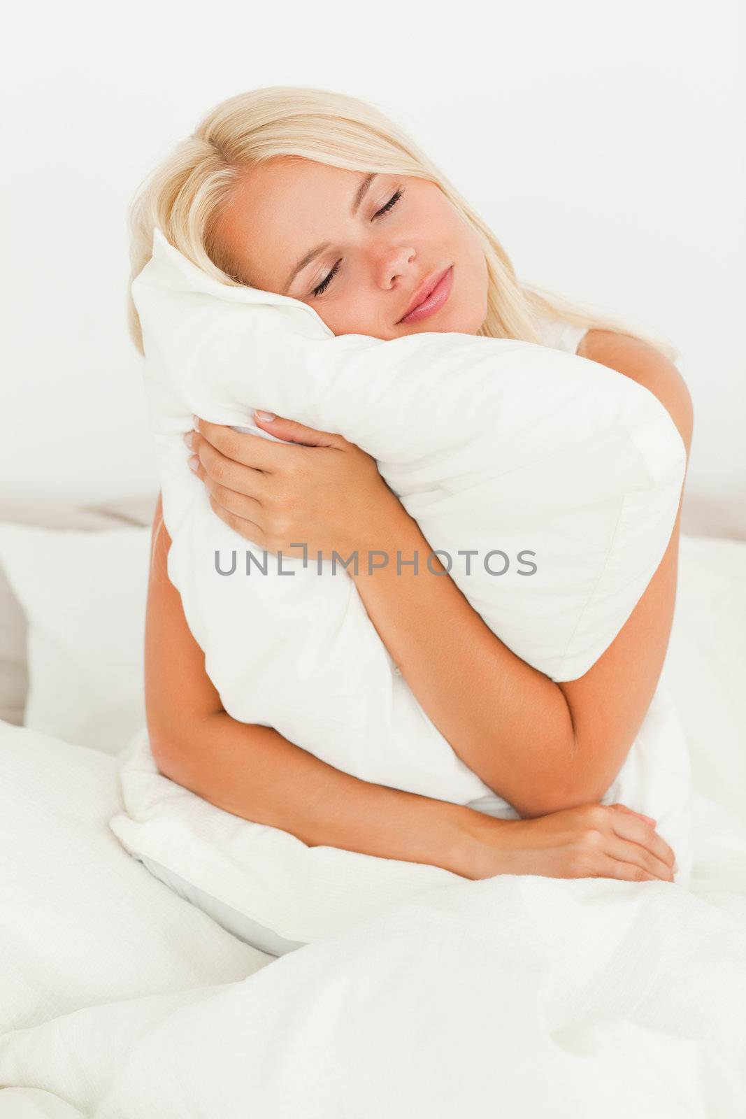 Blonde woman holding a pillow in her bedroom