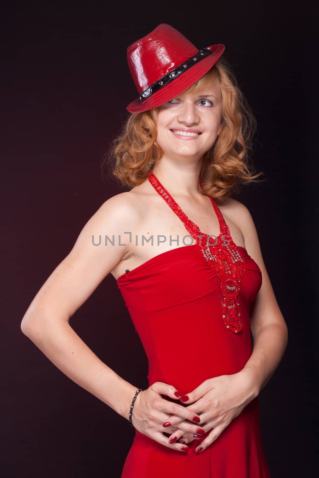 Red-haired girl in a red dress and red hat. Studio photography