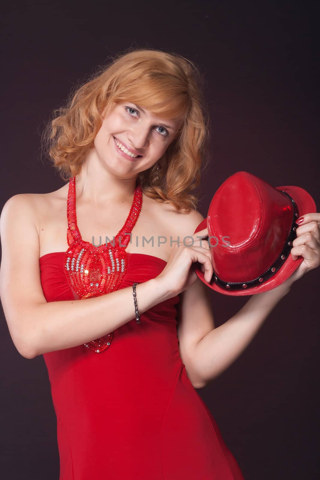 Red-haired girl in a red dress and red hat. Studio photography