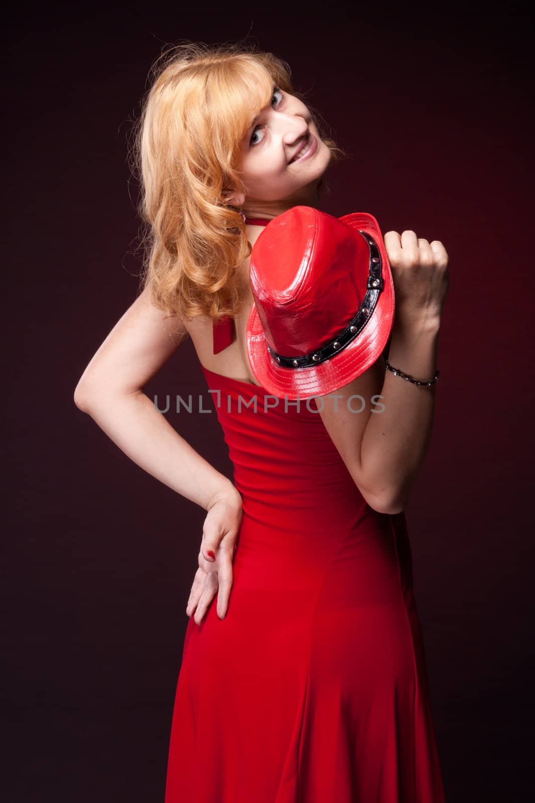 Red-haired girl in a red dress and red hat. Studio photography