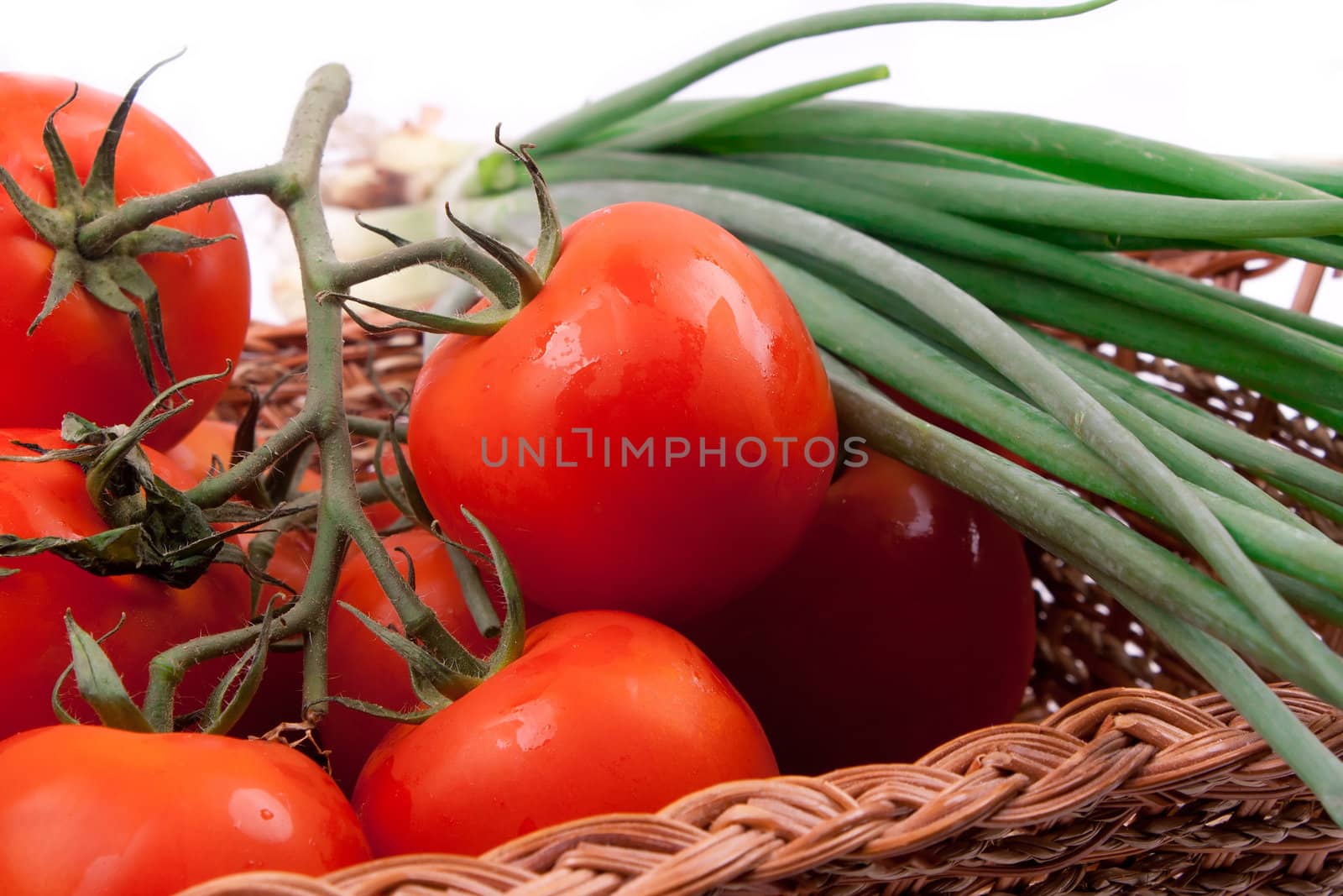 Red tomatoes in a basket on a white background