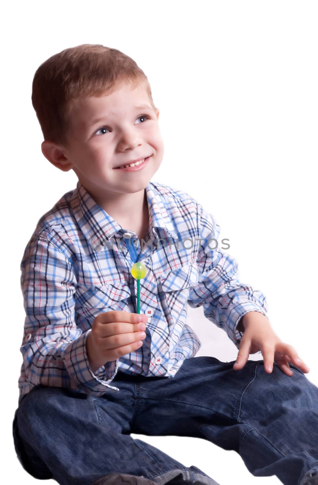 Smiling boy with a lollipop in his hand on a light background