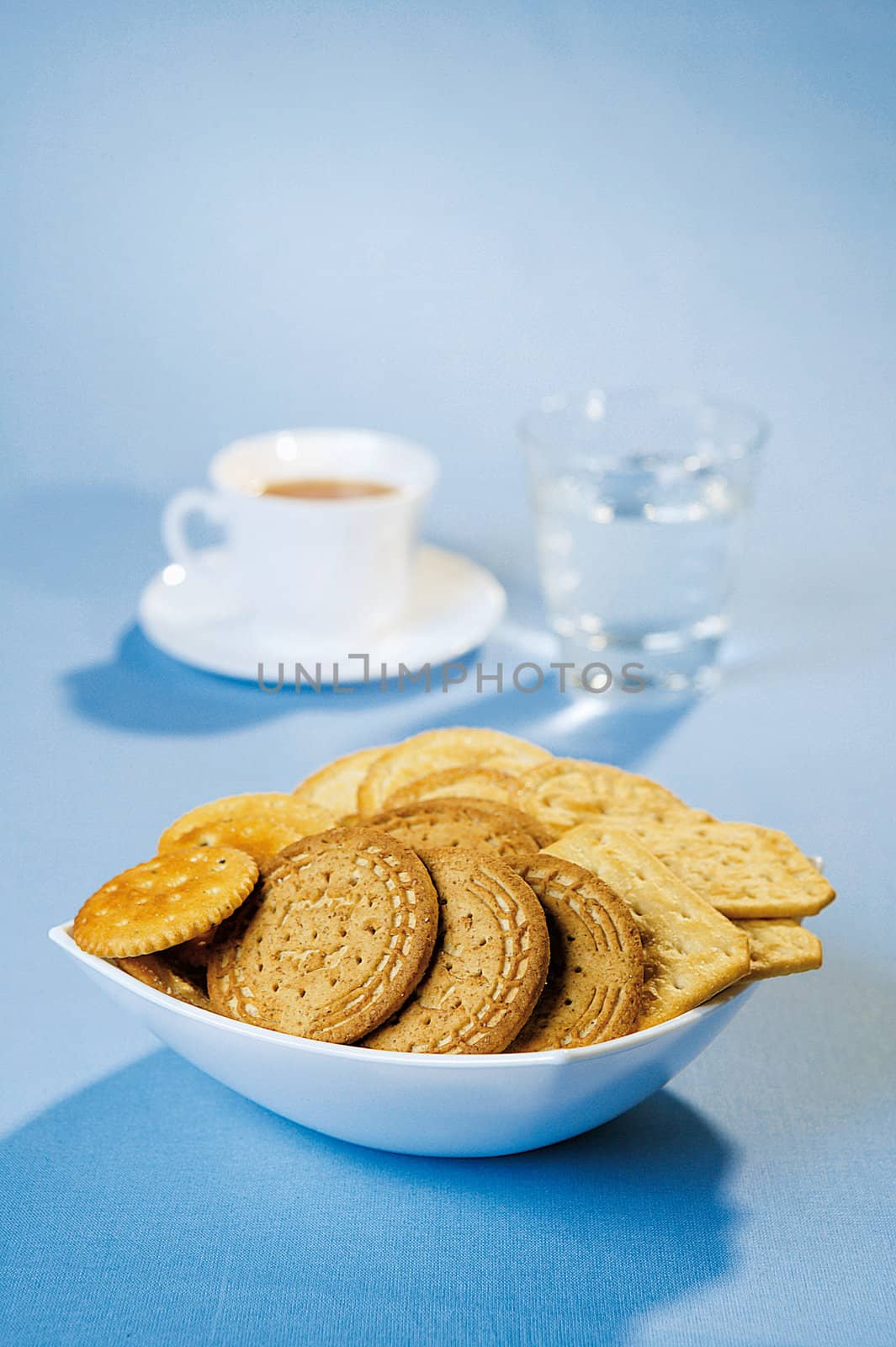 Crackers, coffee and water on a blue table