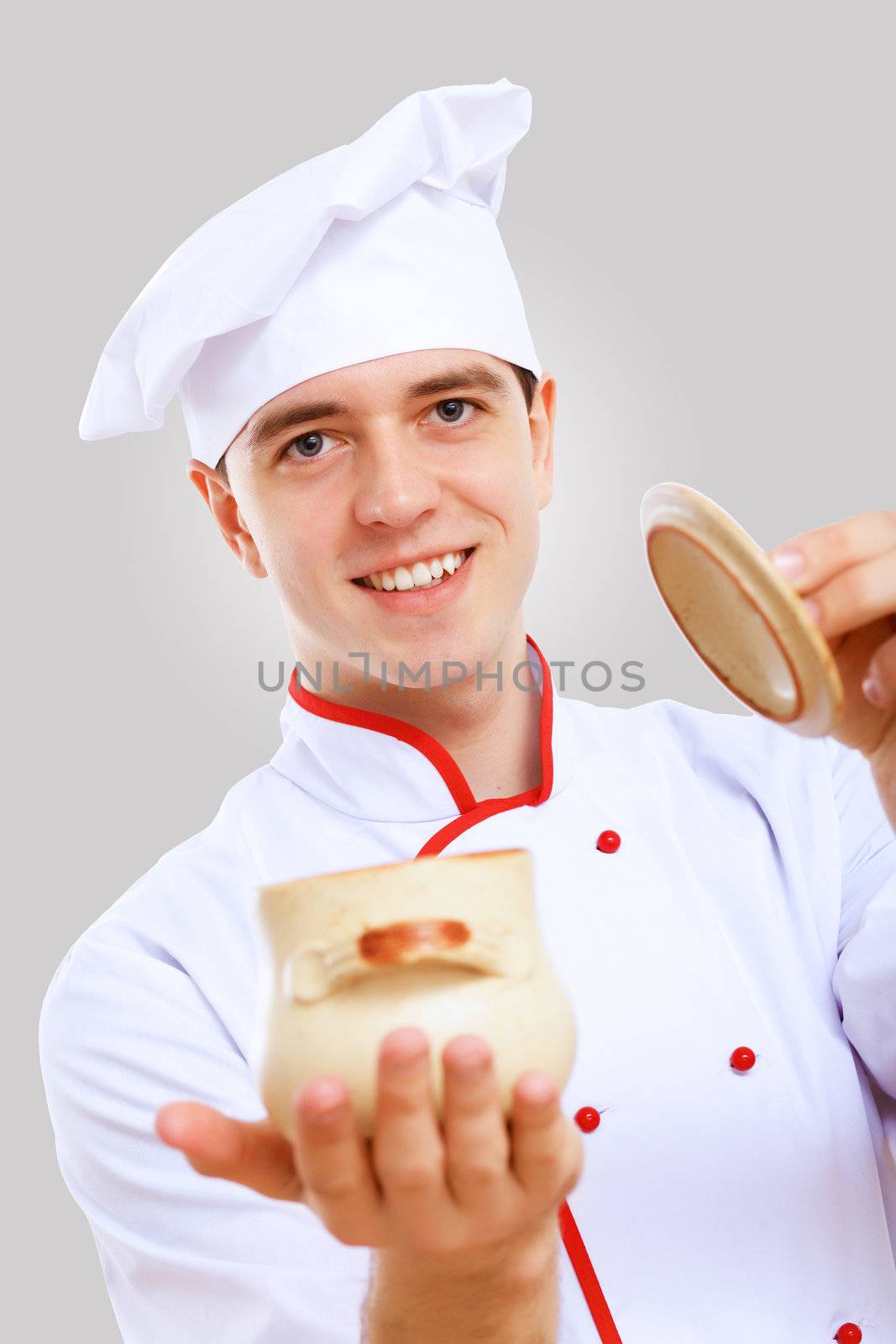 Young male chef in red apron against grey background