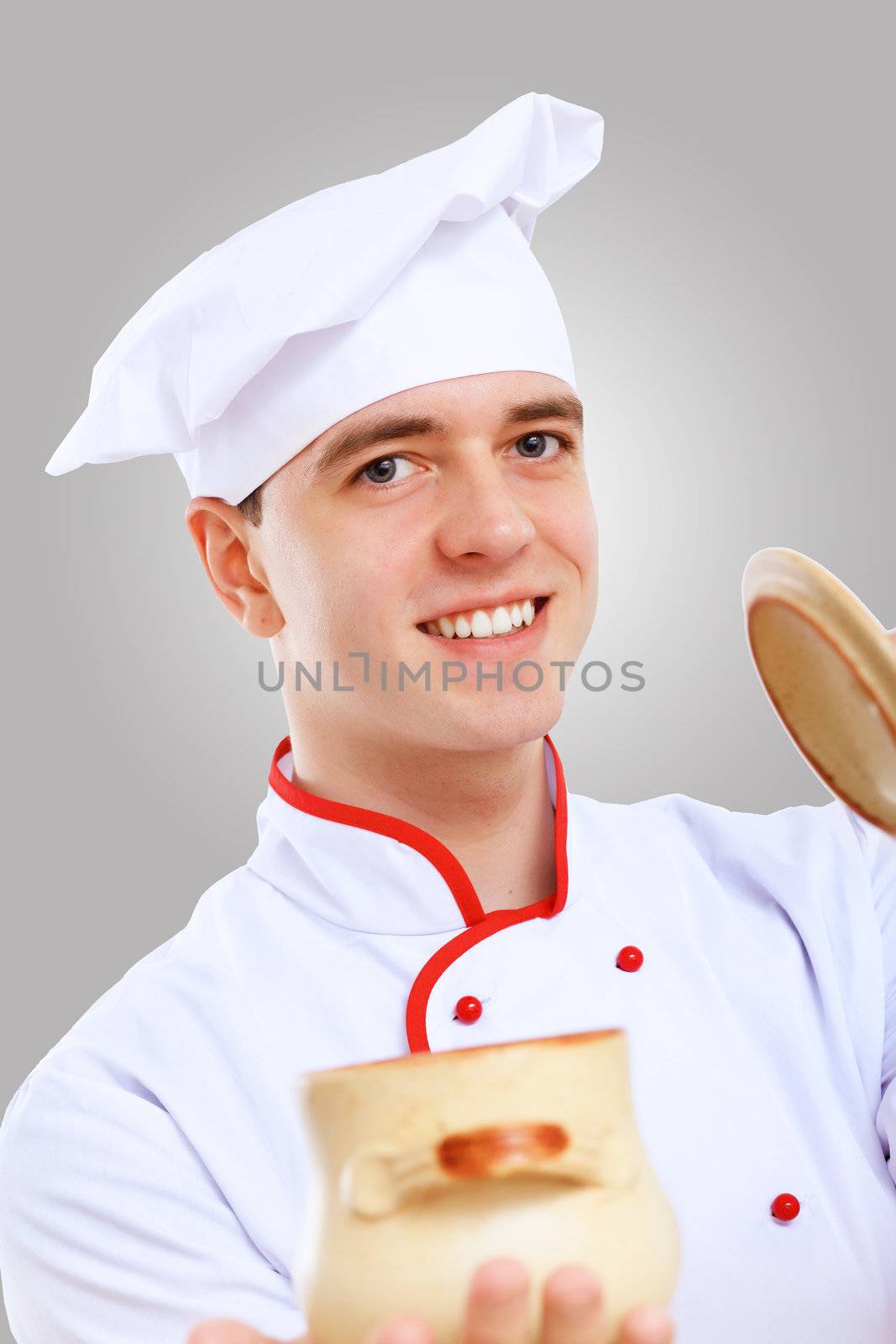 Young male chef in red apron against grey background