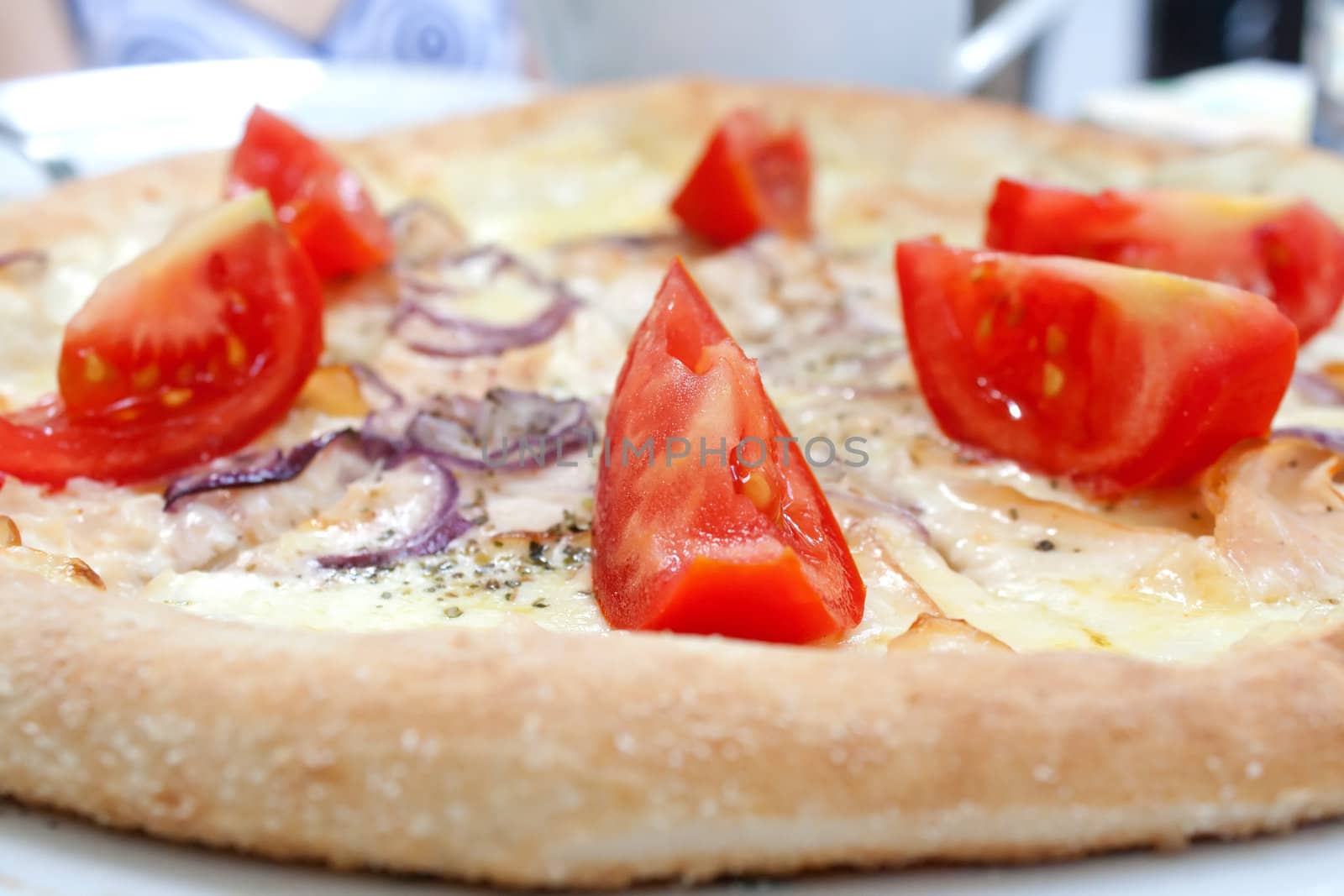 Pizza with large chunks of tomatoes in a cafe shooting