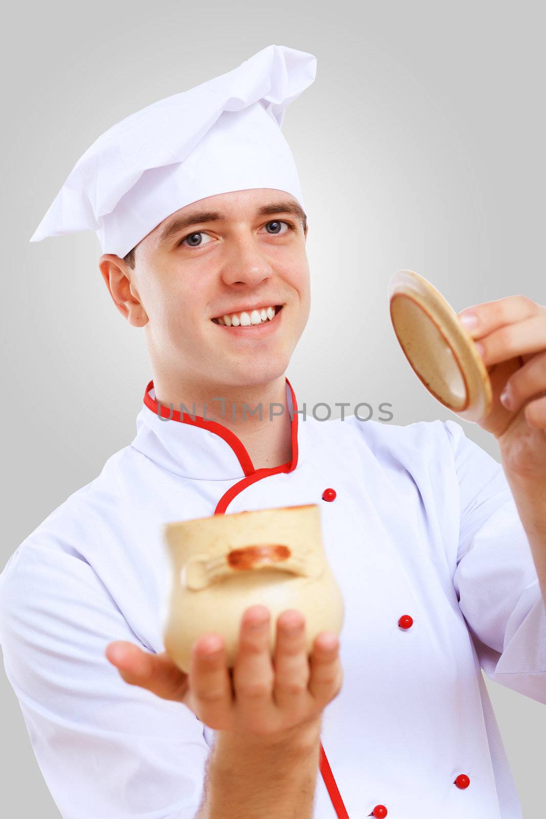 Young male chef in red apron against grey background