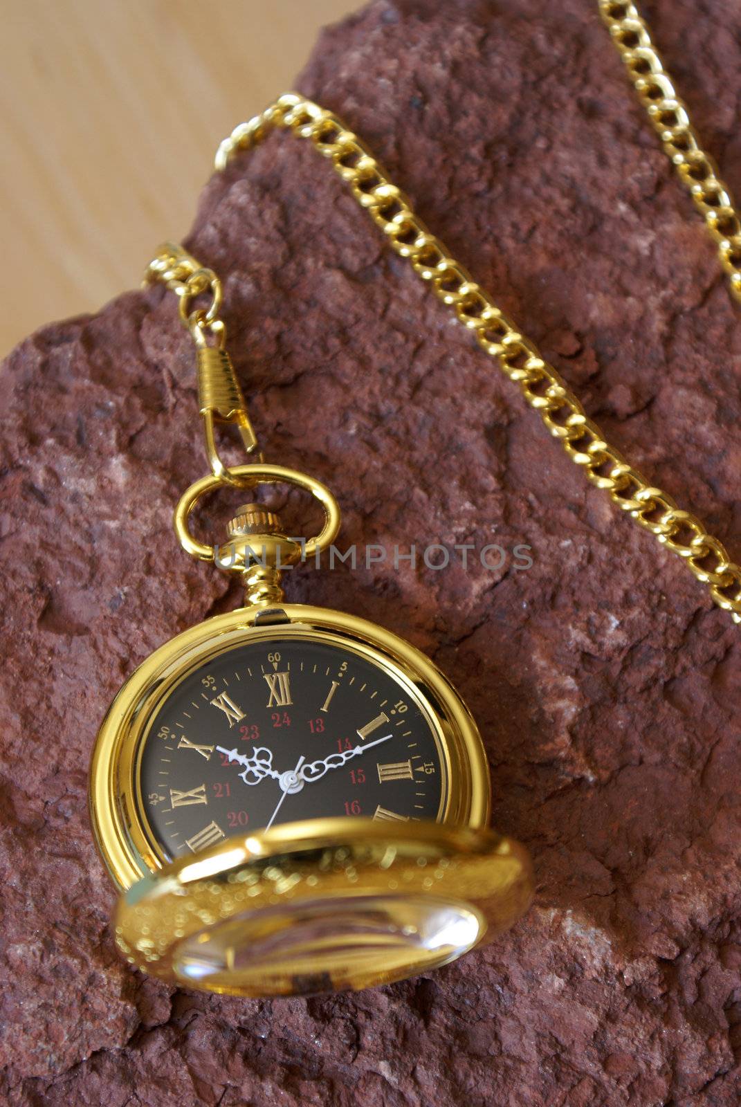 A gold pocket watch on a red sandstone.