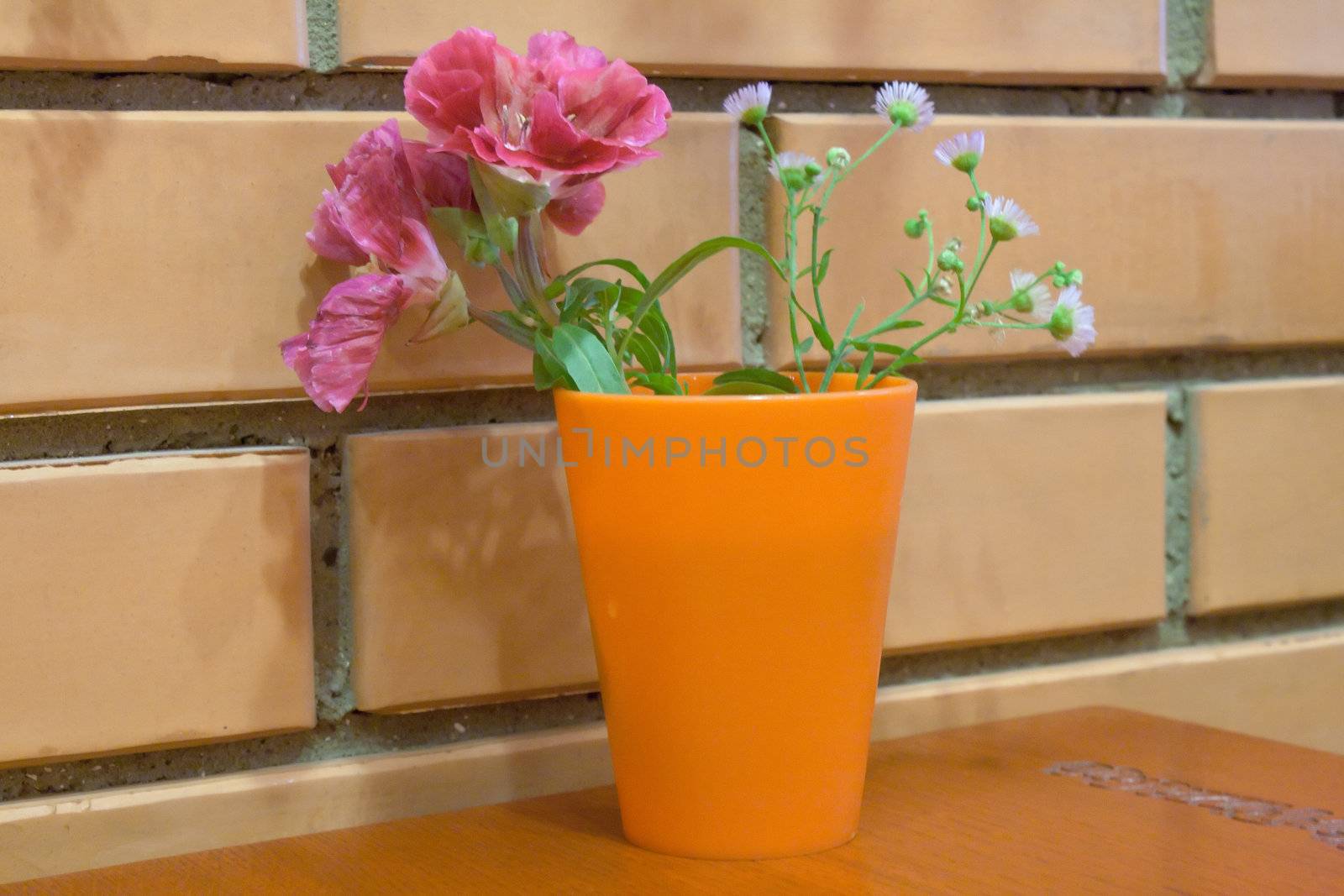 Glass with flowers near a brick wall in a cafe shooting
