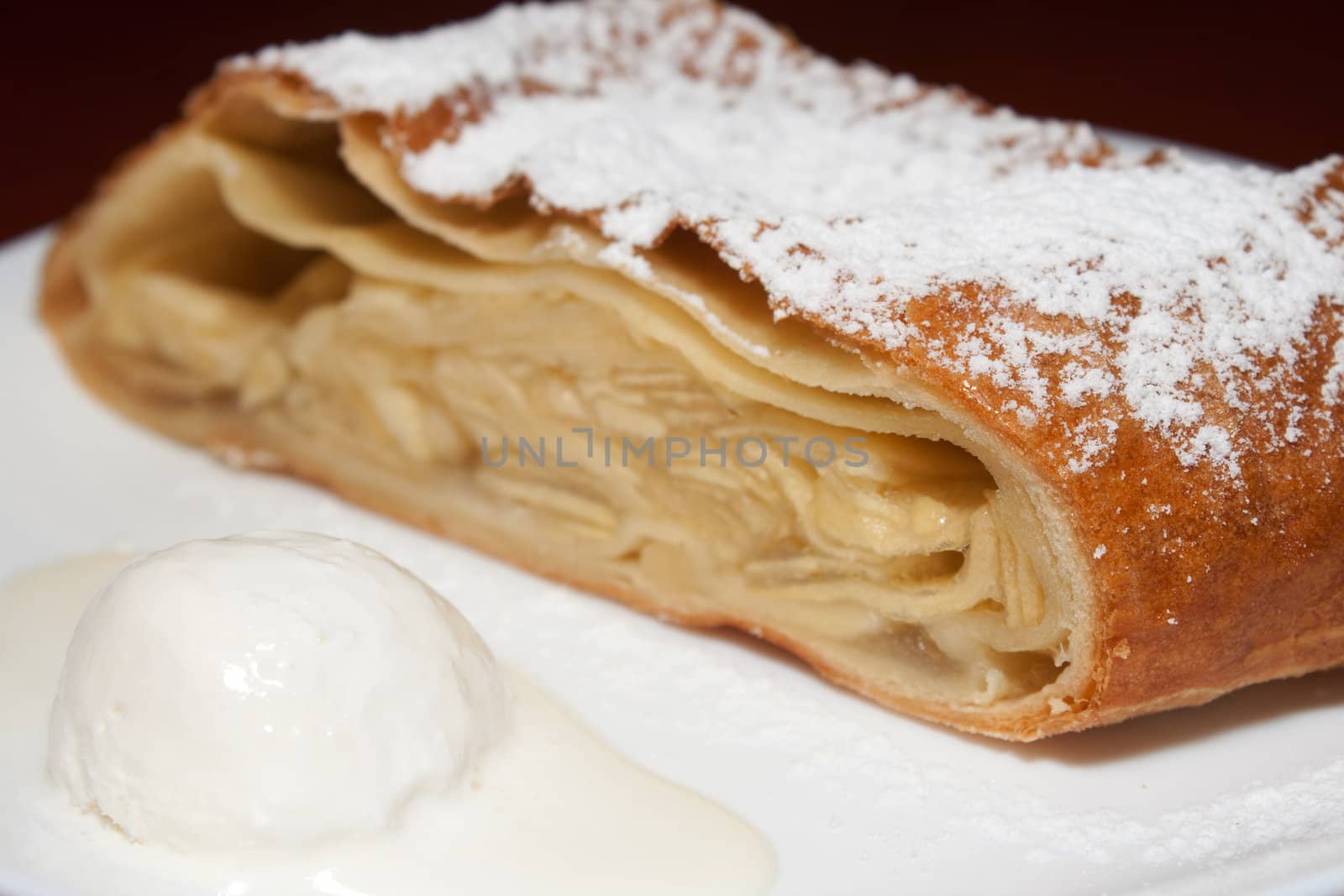 Apple pie with powdered sugar and ice cream at the forefront in the cafe shooting