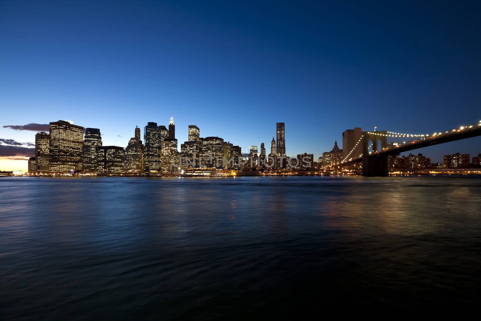 The New York City skyline at twilight w Brooklyn Bridge