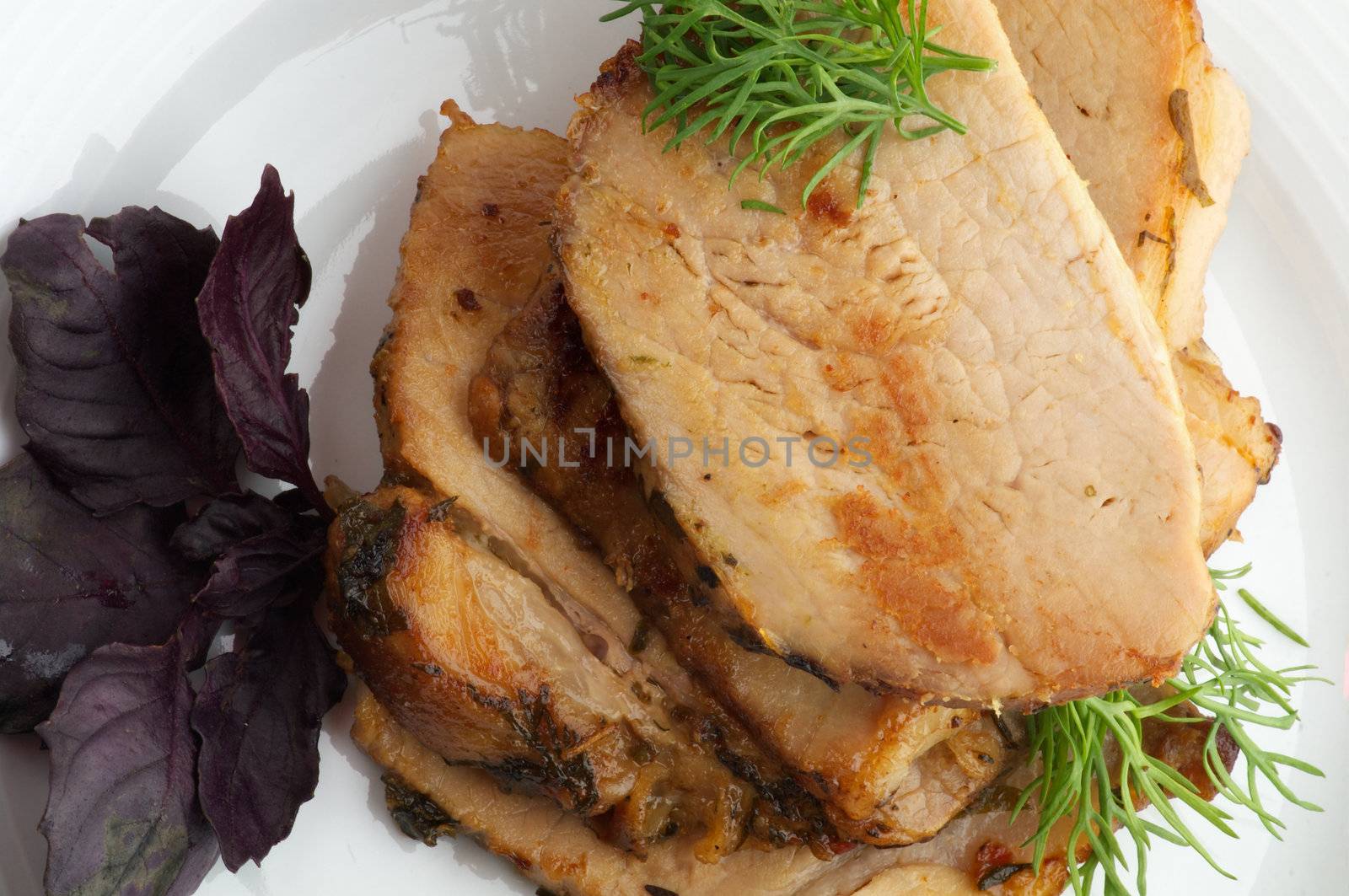 Slices of Ripe Roasted Pork with Greens on white plate top view