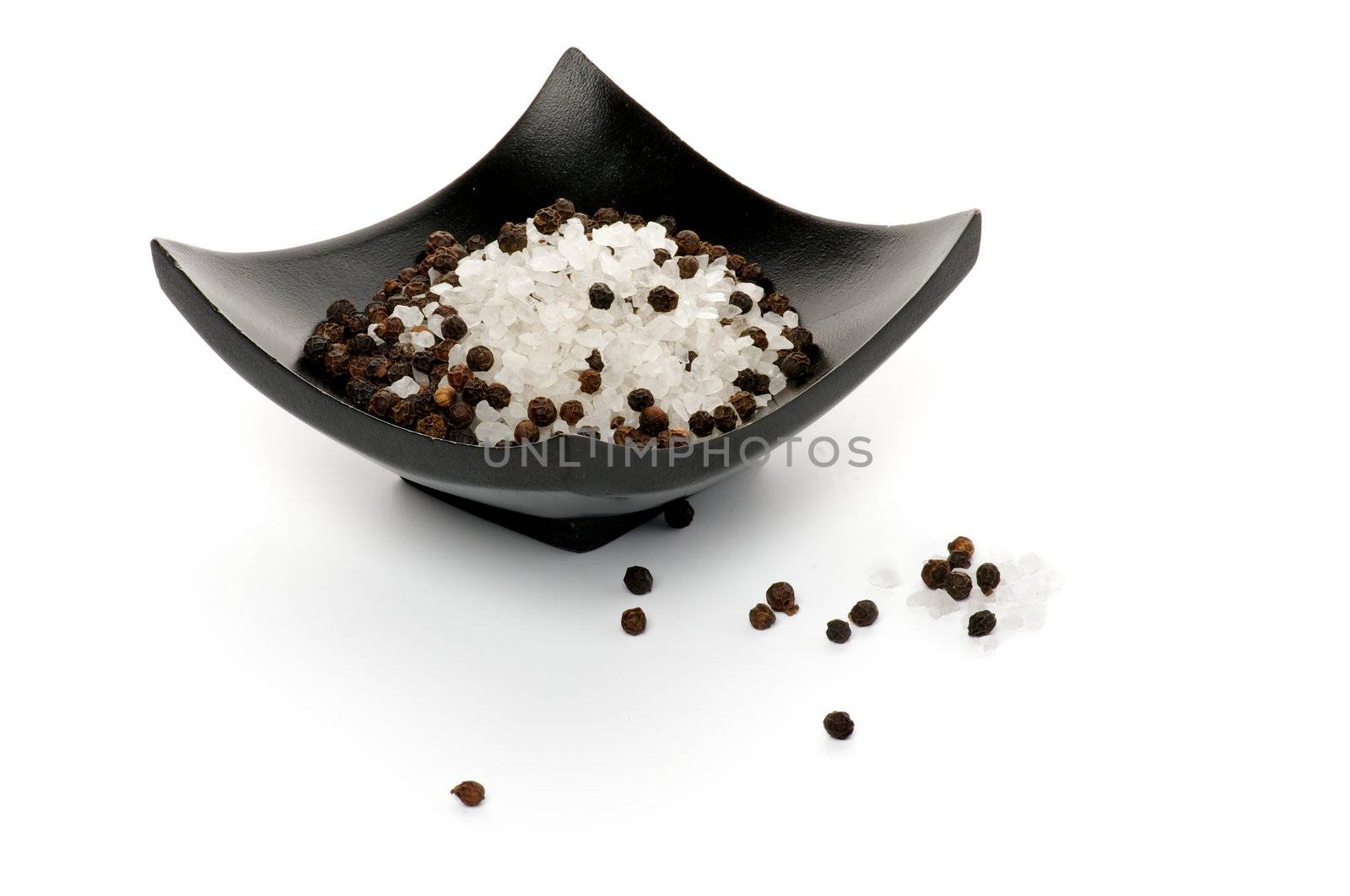 Whole Black Peppercorns and Crystal Sea Salt on Black Plate isolated on white background
