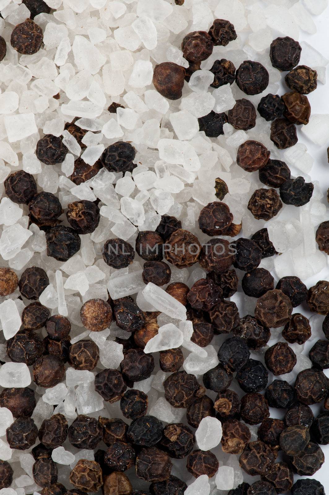 Background of Whole Black Peppercorns and Crystal Sea Salt closeup
