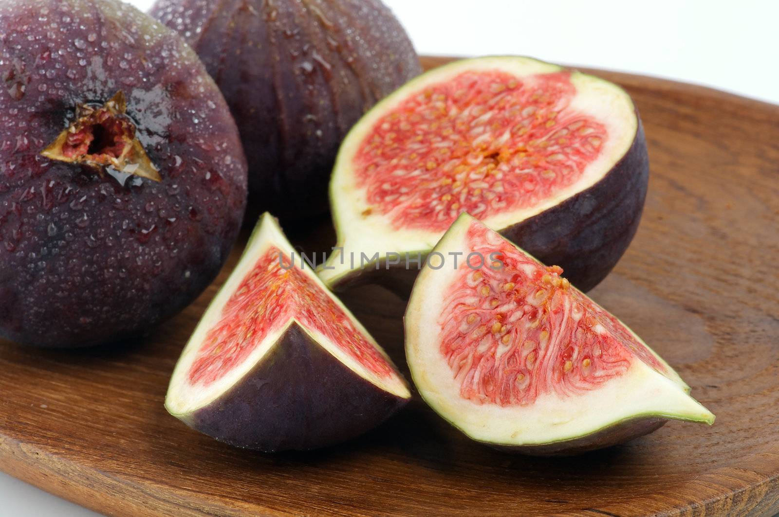 Perfect Ripe Figs Full Body and Slices with Droplets closeup on Wooden Plate 