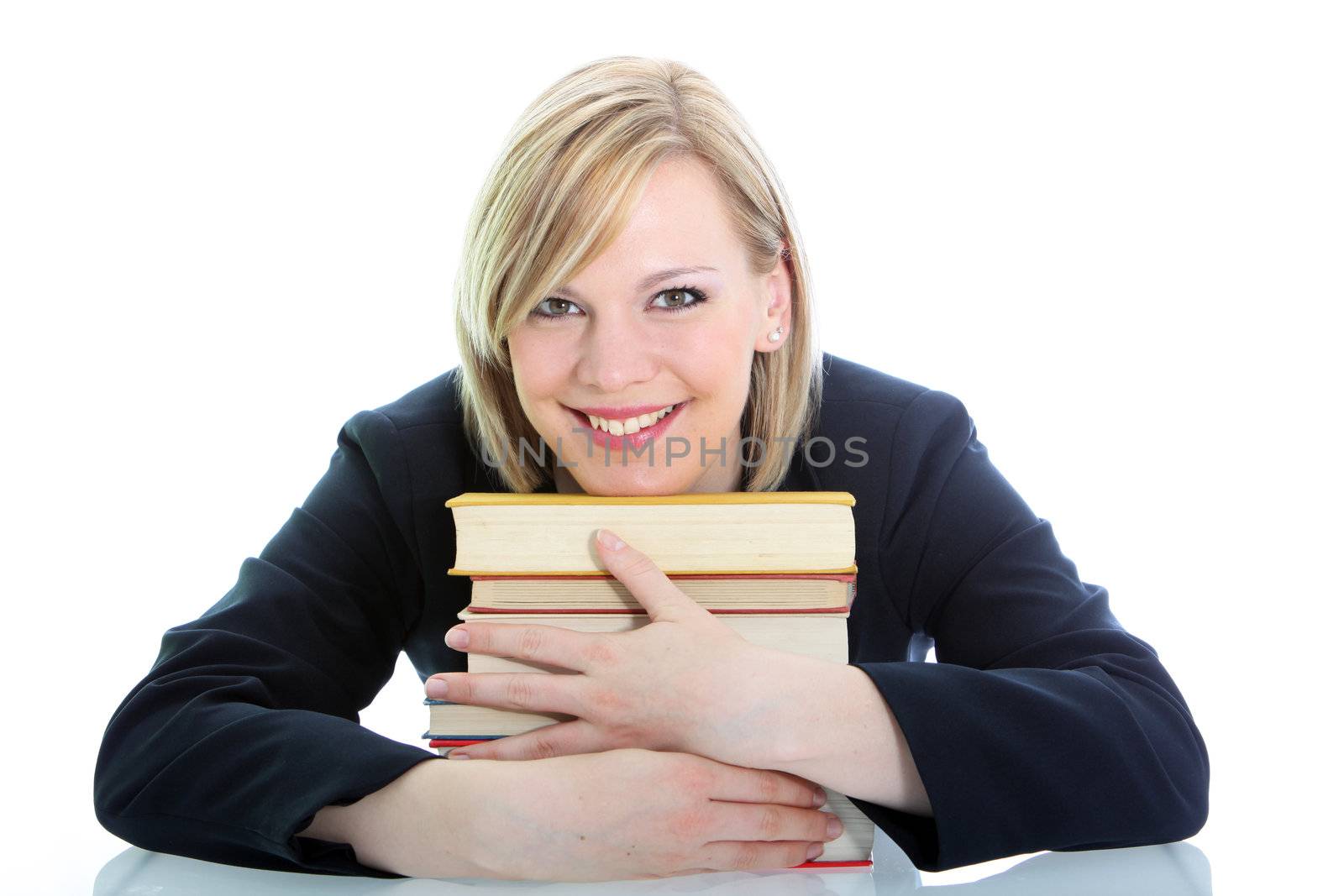 Smiling student with a positive attitude sitting at her desk hugging her text books isolated on white