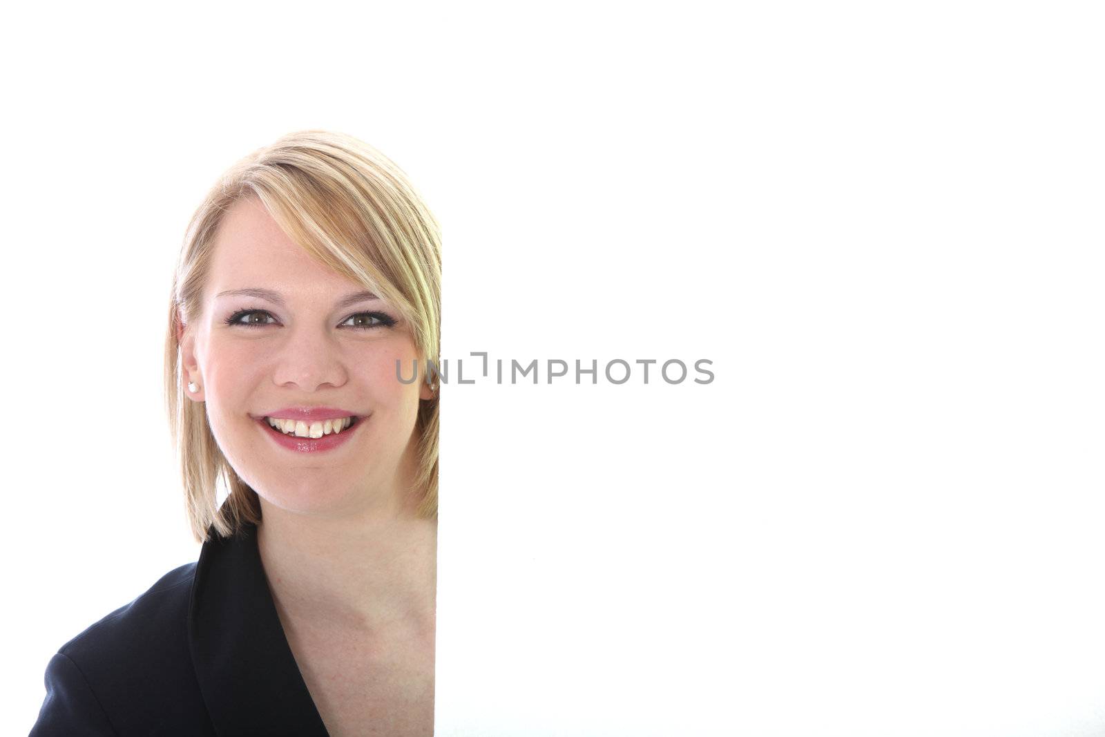 Happy woman standing alongside a large blank white placard or board with copyspace for your text Happy woman standing alongside a large blank white placard with copyspace for your text