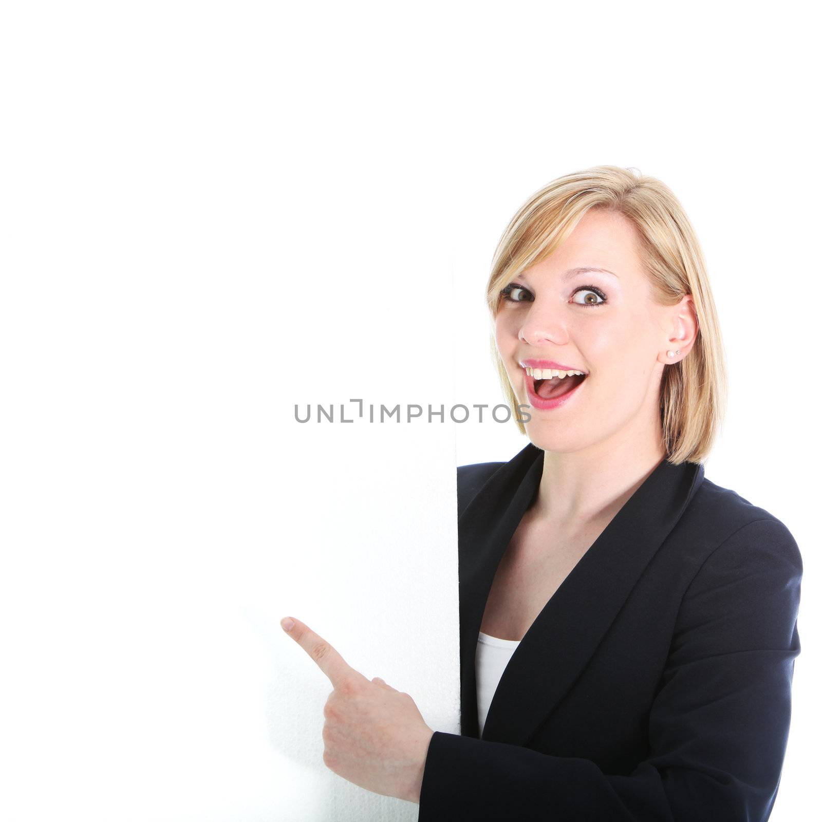Excited young blonde woman pointing to a blank sign with her finger endorsing your advertisement or text