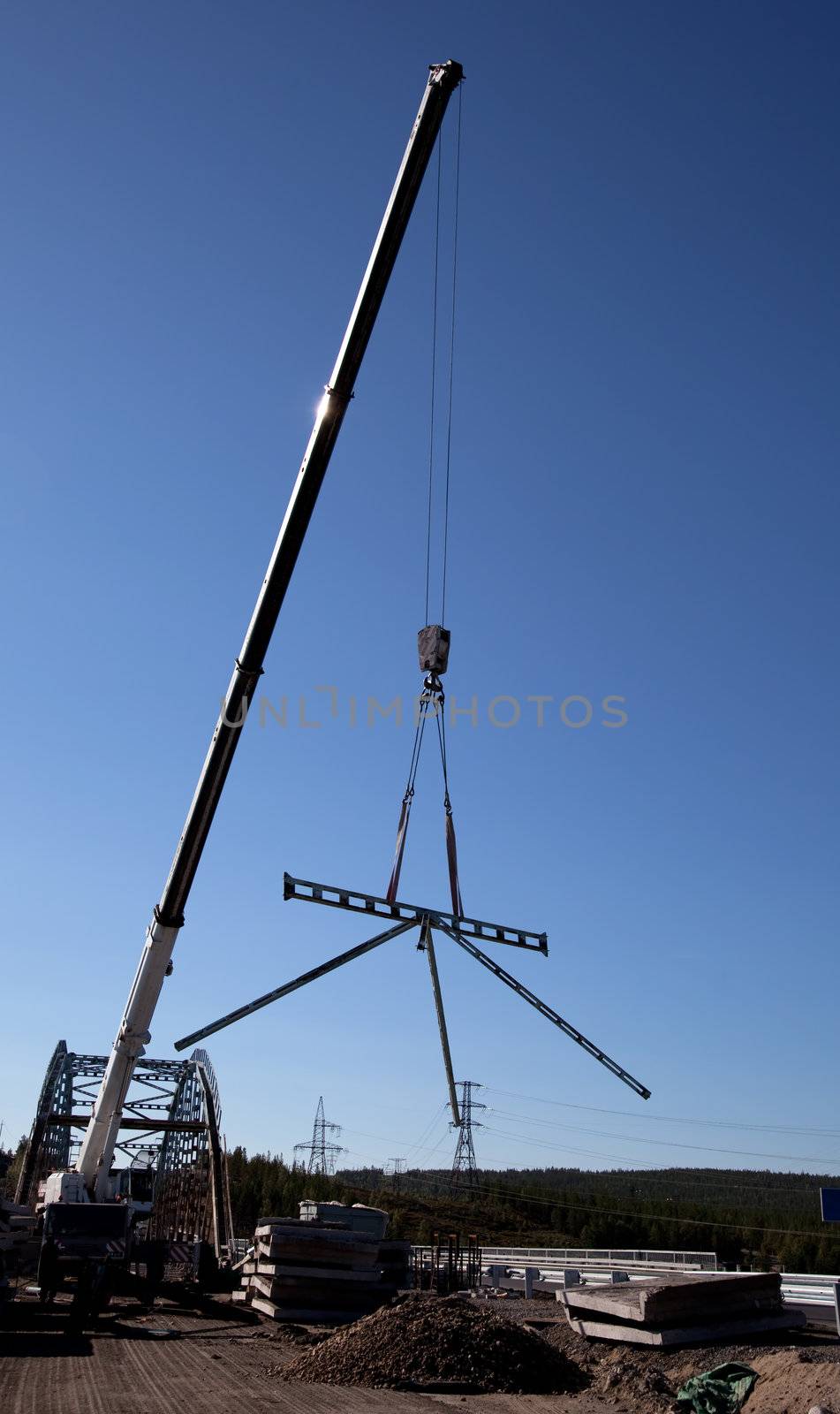 
Mobile crane lifts part of the bridge against the blue sky
