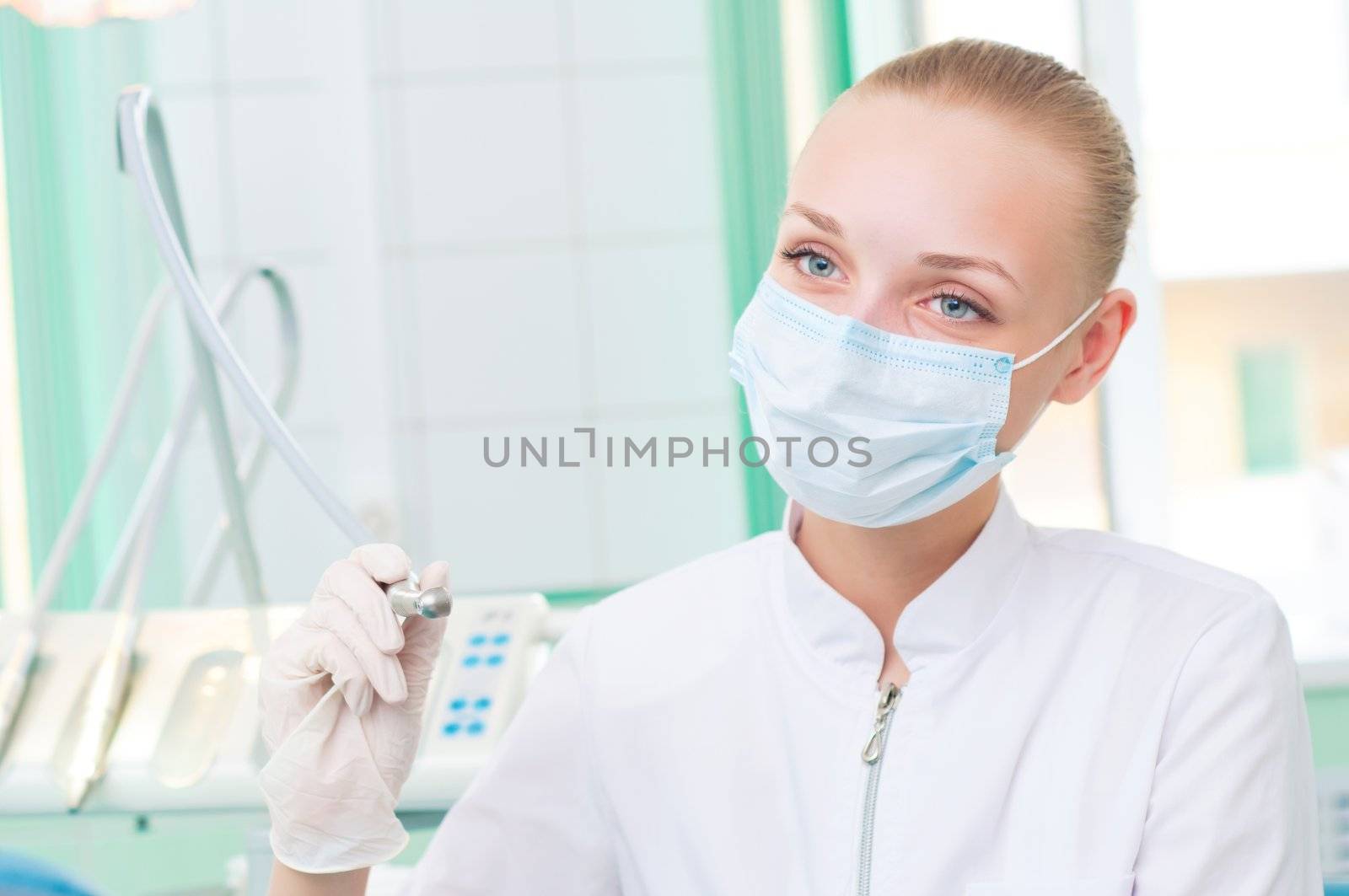 female dentists in protective mask holds a dental drill, the doctors at work