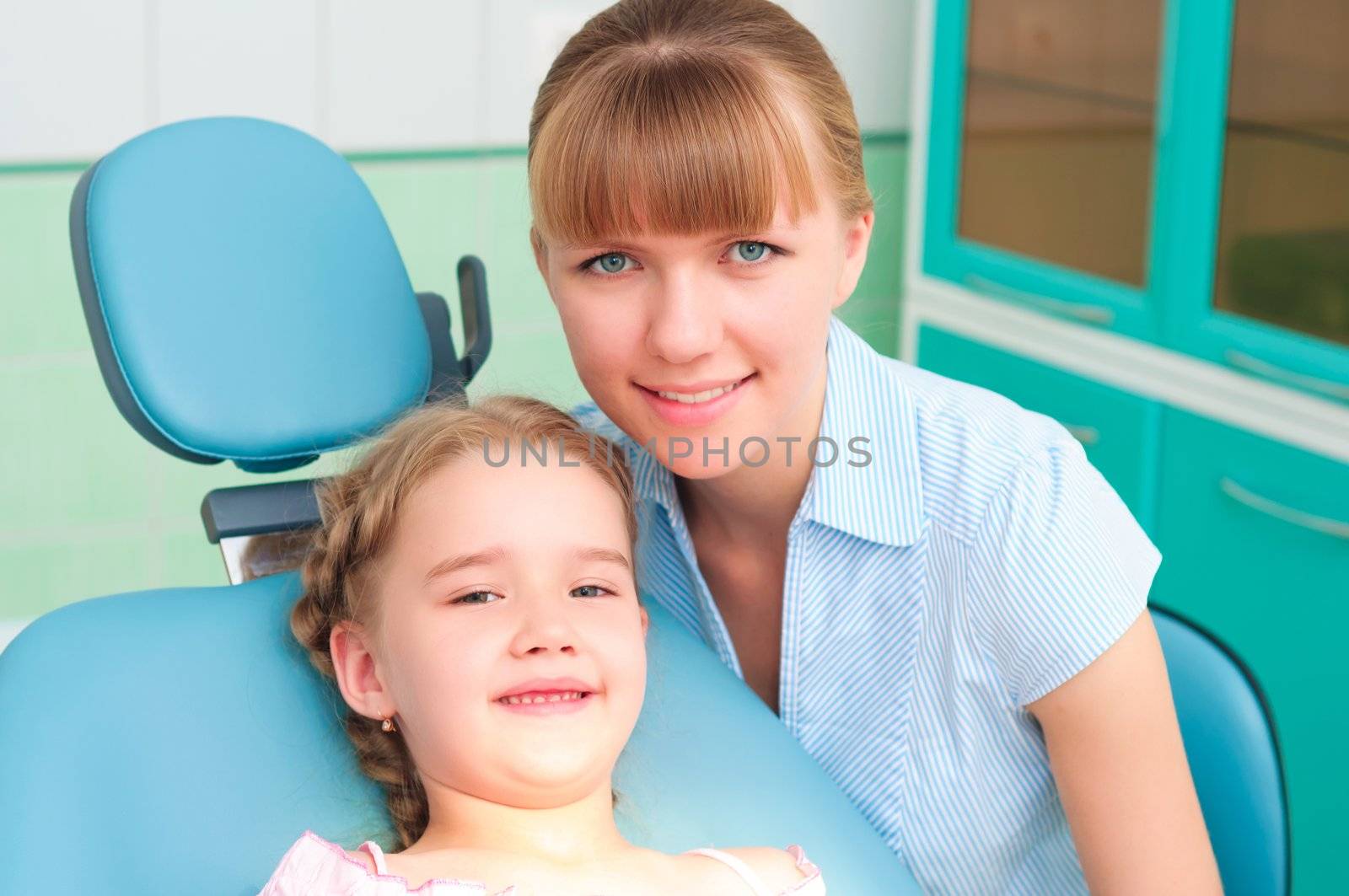 mother and daughter visit the dentist, the child is sitting in the dental chair and mother near