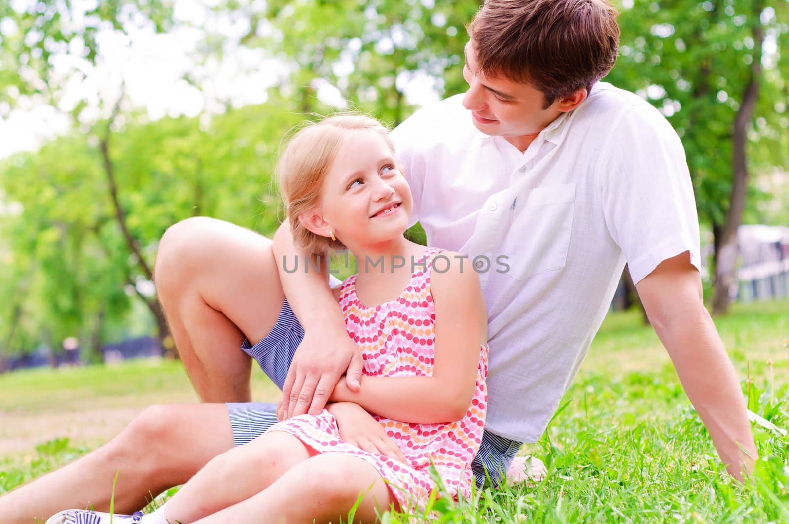 Father and daughter sitting together on the grass, and spend time with family