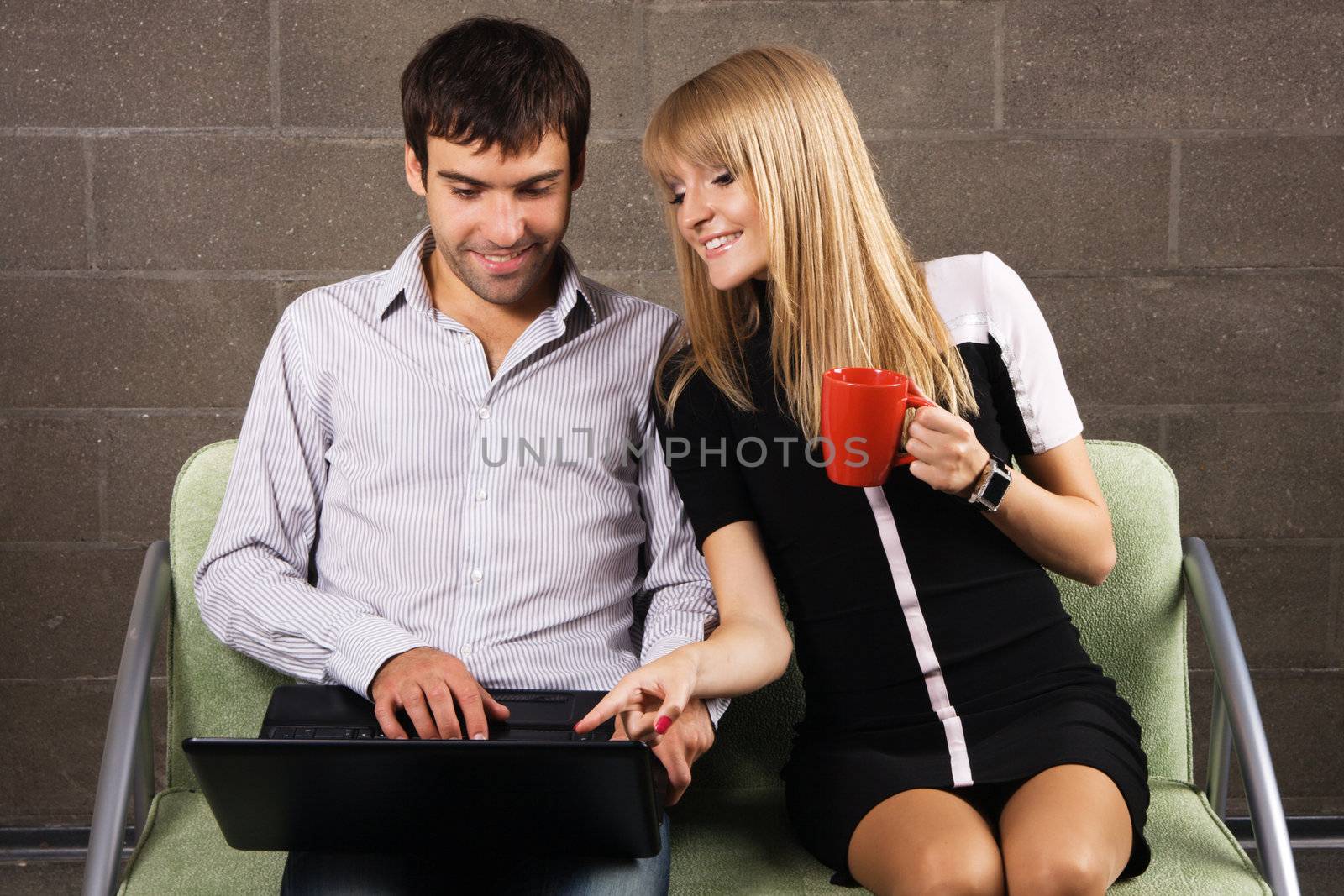 Cheerful man and woman working with a laptop by Gdolgikh