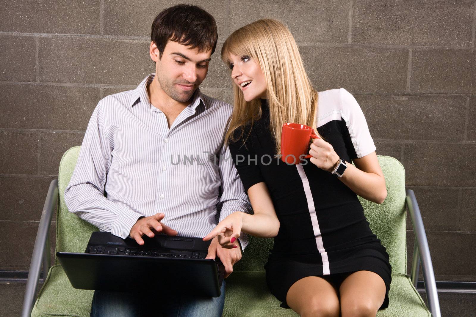 Young man and woman sitting with a laptop by Gdolgikh