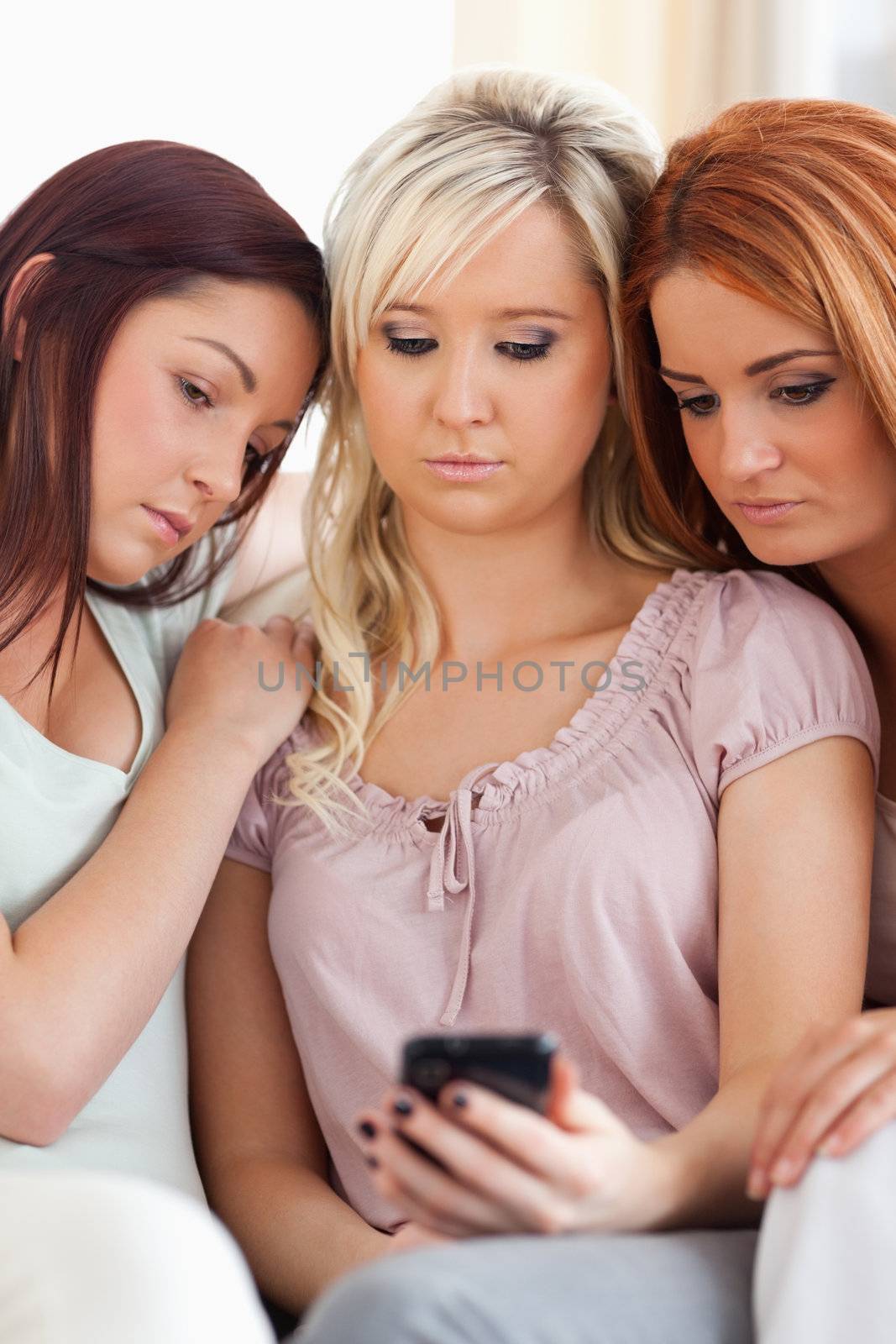 Cute Friends sitting on a sofa with a mobile in a living room