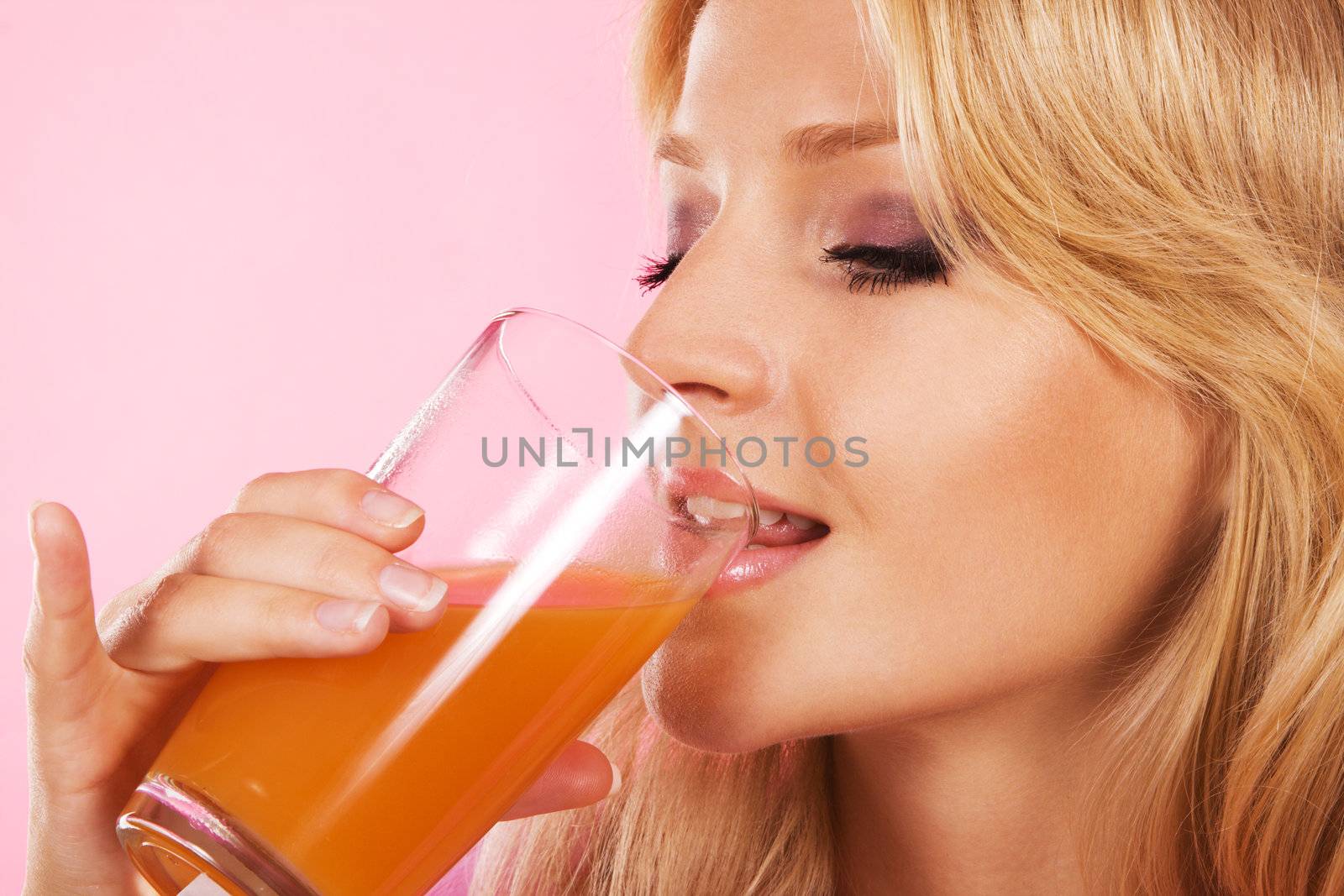 Closeup portrait of a lovely blonde drinking fresh juice 