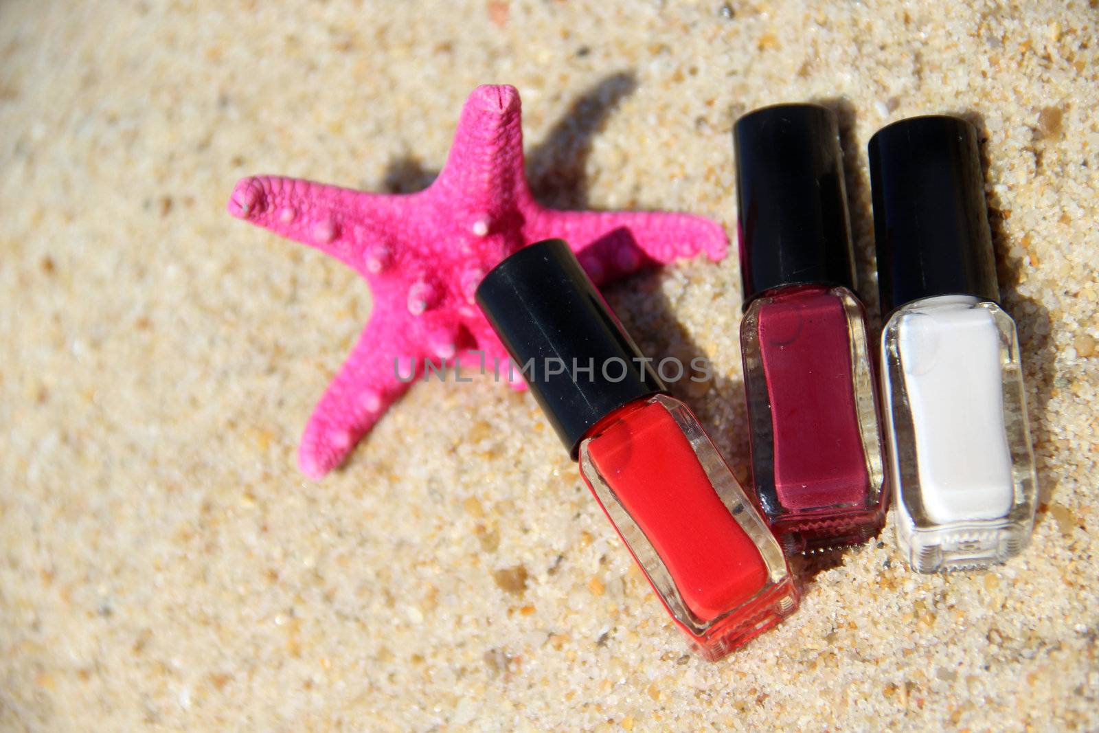 Three nail polish bottle on the beach and pink starfish