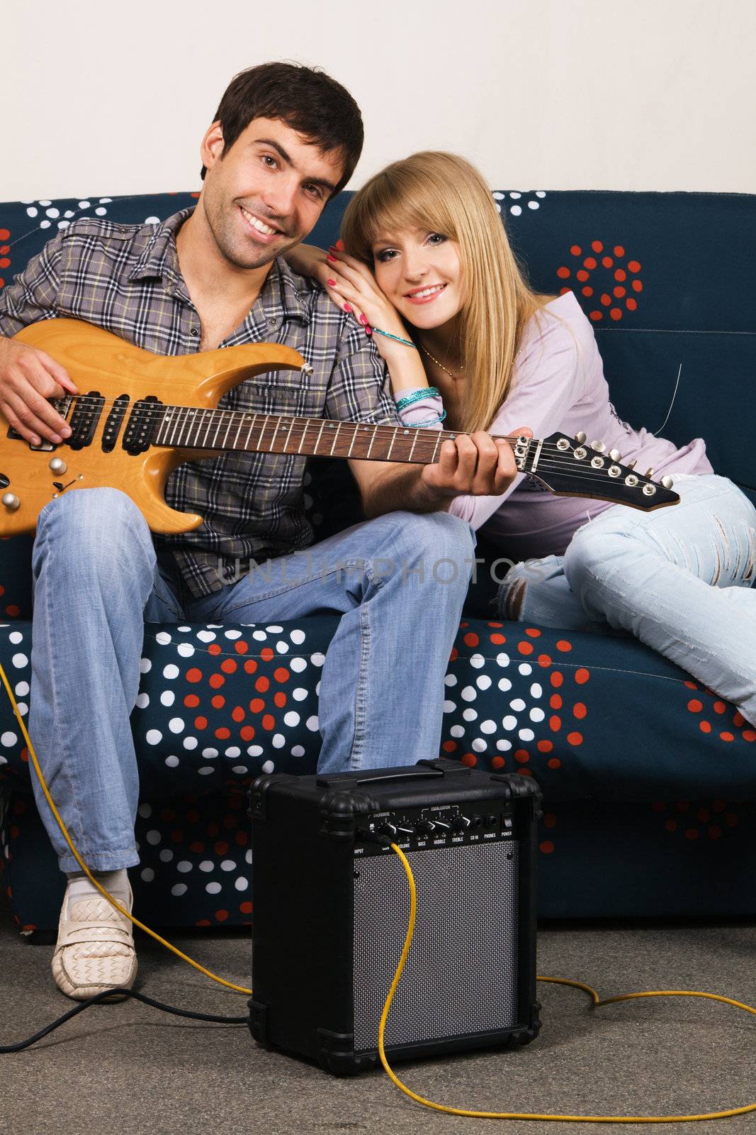 Romantic young couple resting on a sofa with a music 
