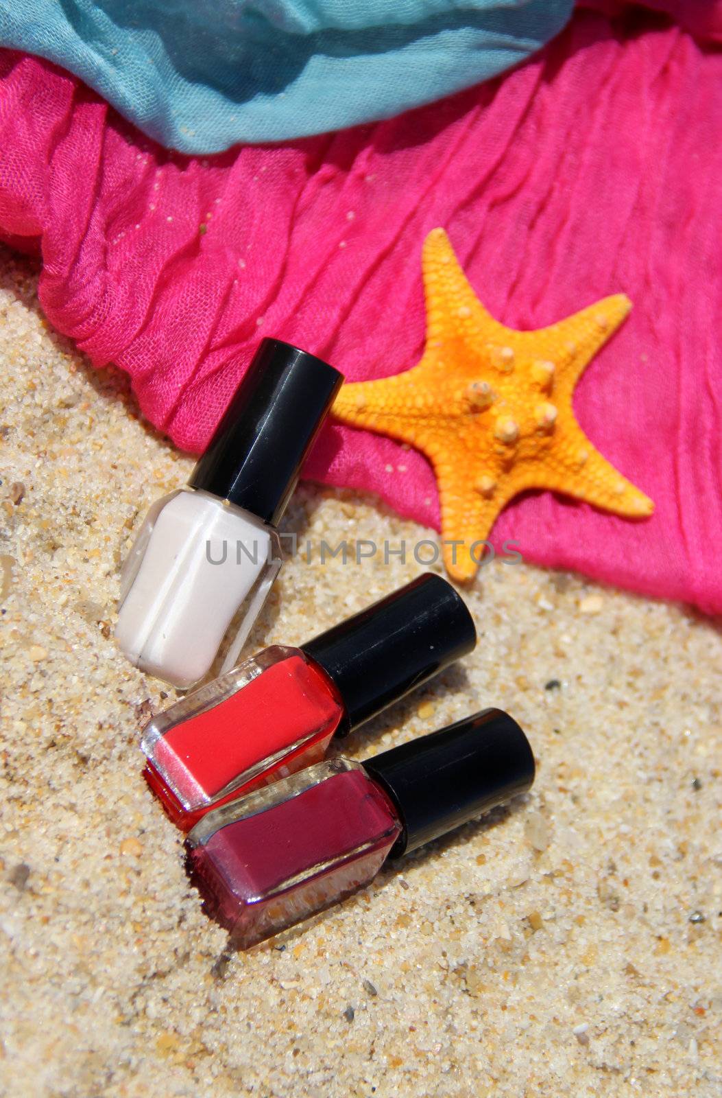 Three nail polish bottle on the beach, scarfs and pink starfish