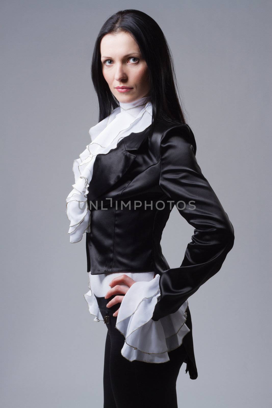 Elegant woman in tailcoat against gray background