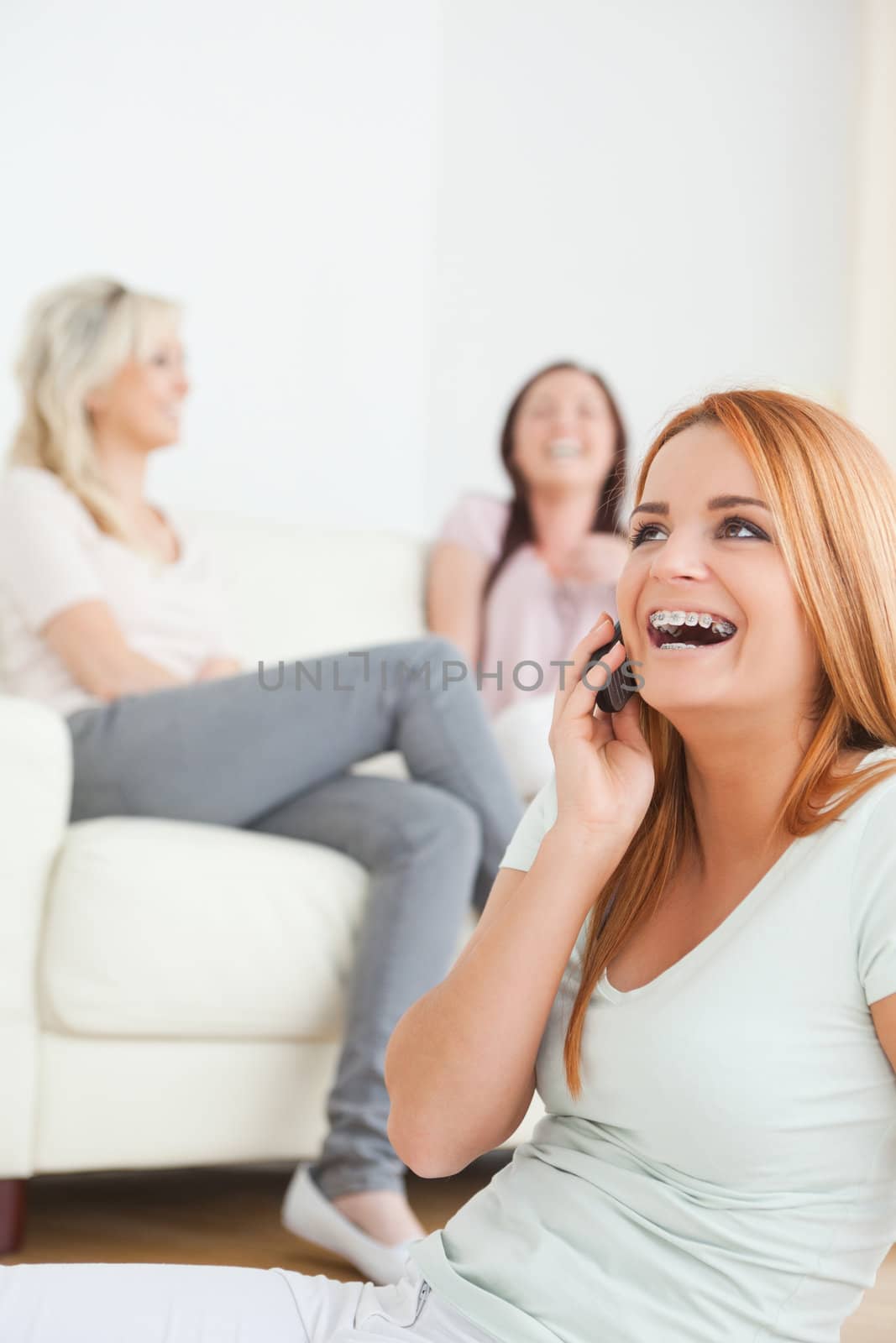 Laughing woman with a cellphone separated from the others in a living room