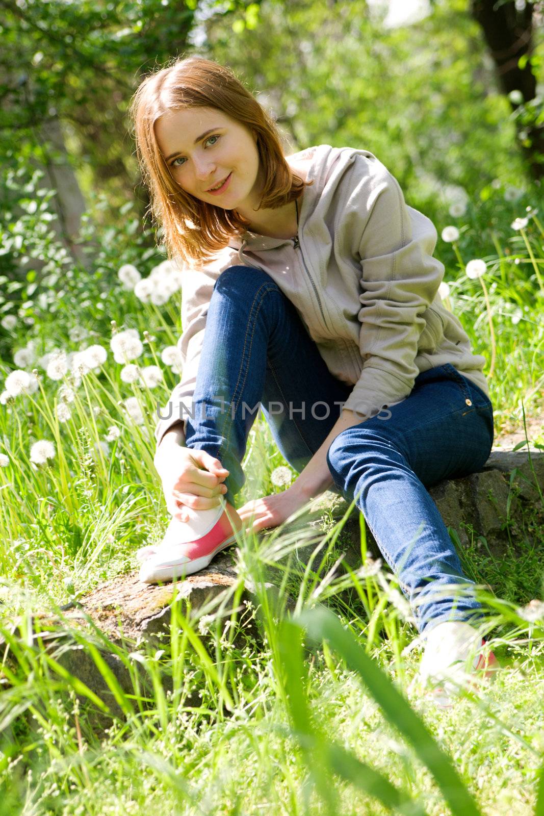 Beautiful young woman sitting in dandelions by Gdolgikh