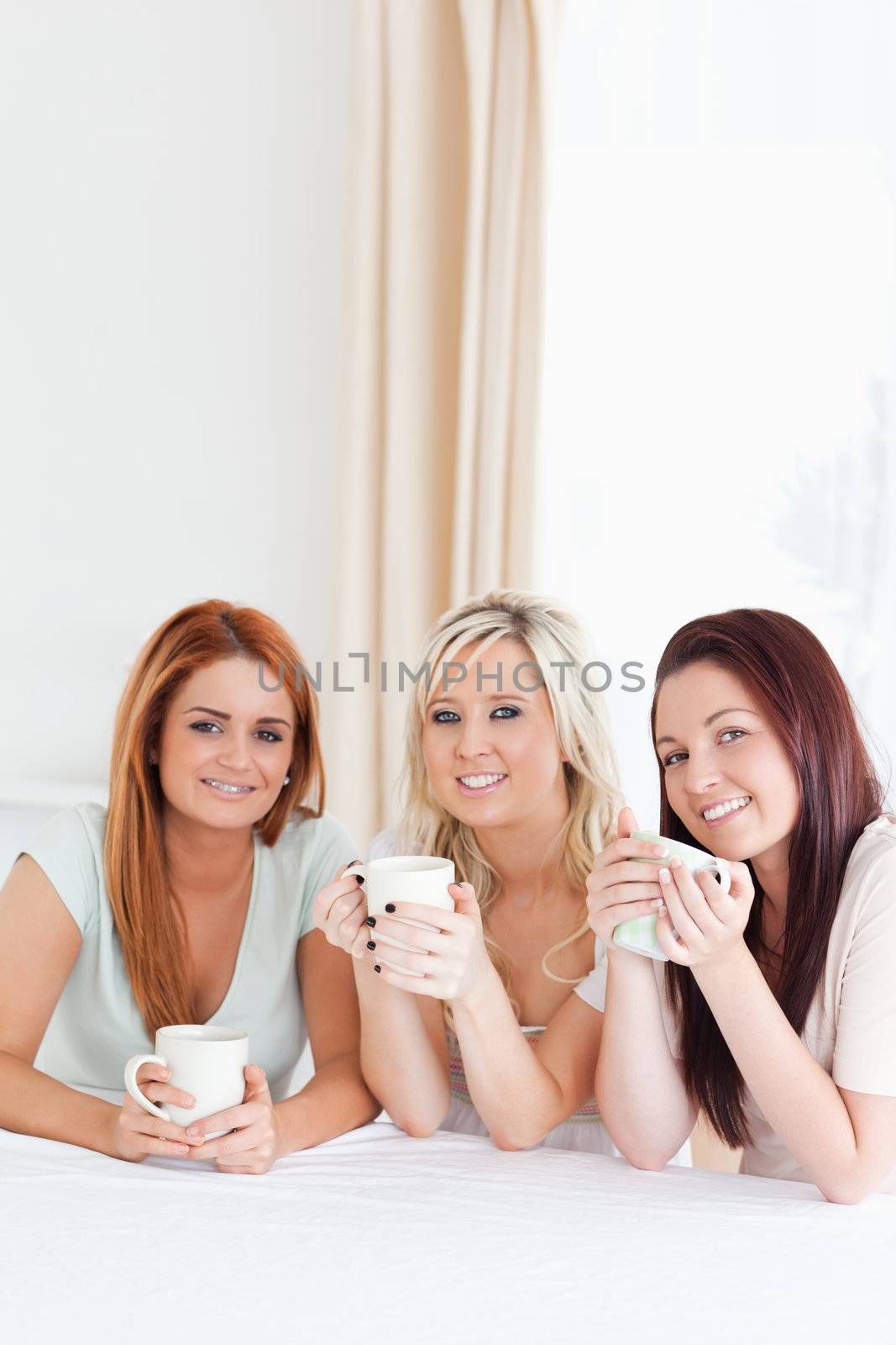Smiling Women sitting at a table with cups in a kitchen