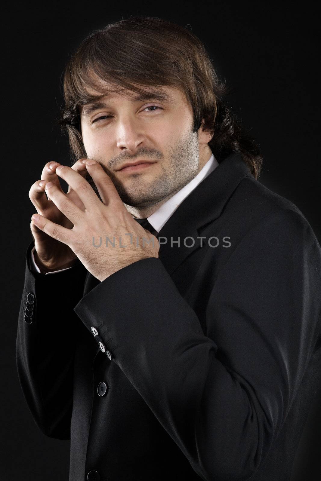 Sly man in elegant suit against black background