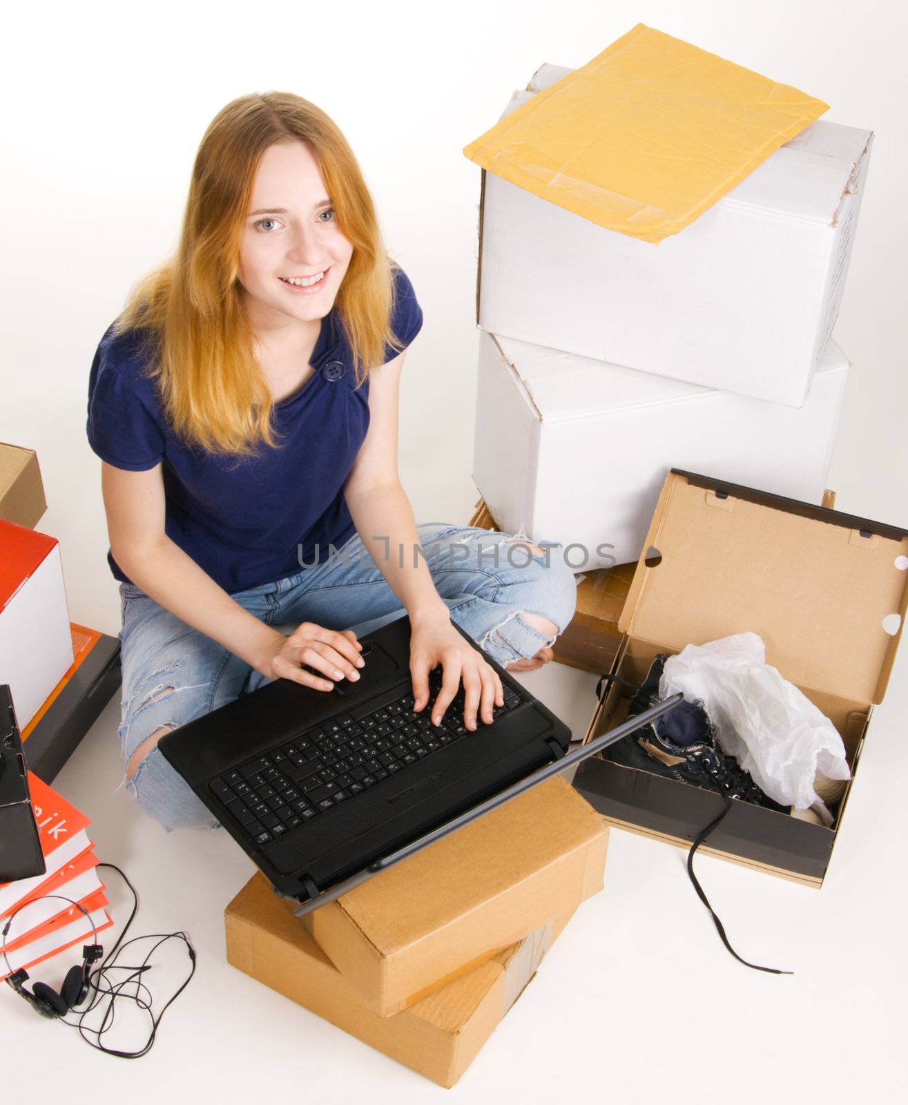 Young beautisul woman surrounded by delivered orders, surfing an online store at her laptop