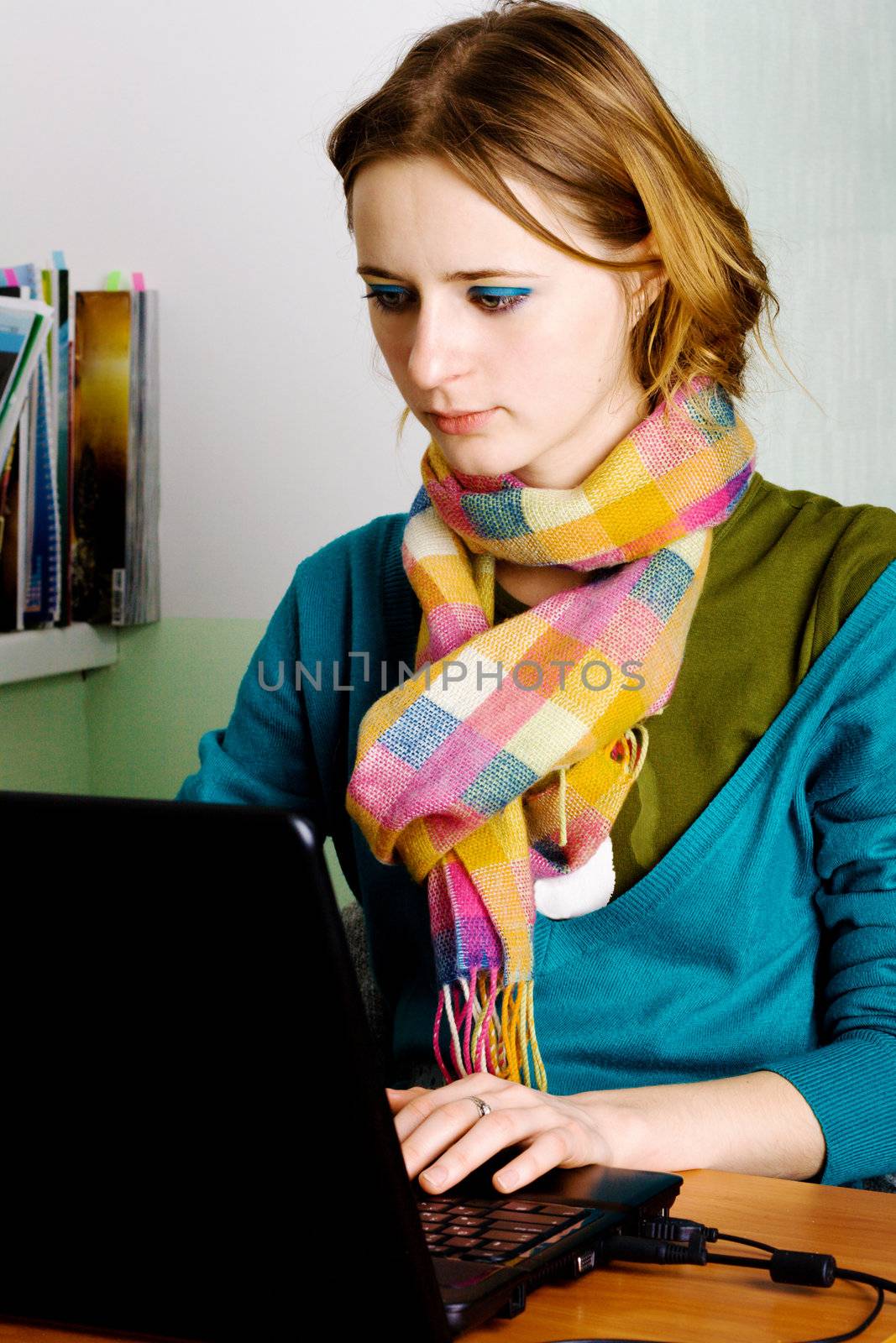 Pretty young woman in casual clothing working at laptop
